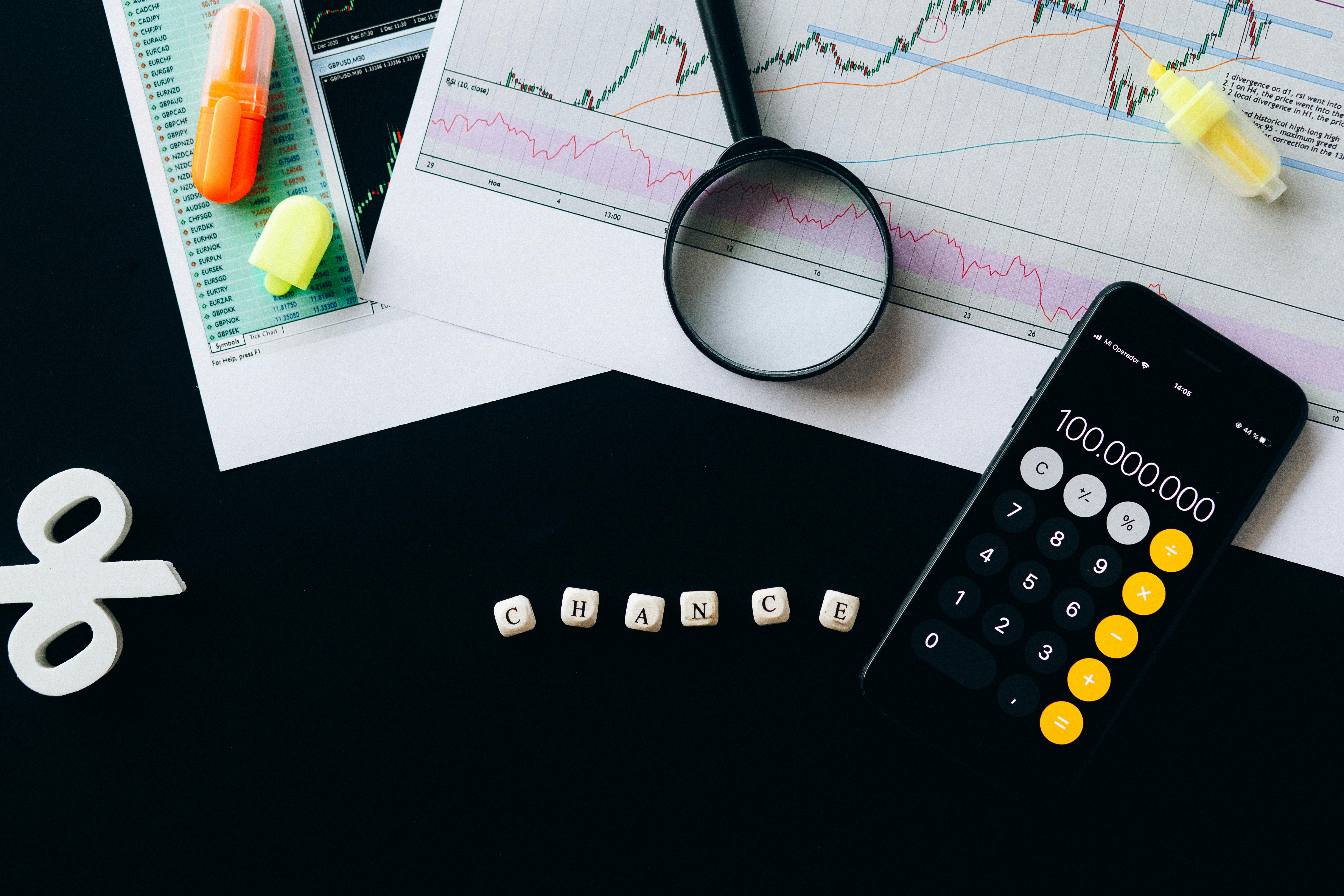 Graphique de performance, loupe et calculatrice posés sur un bureau sombre