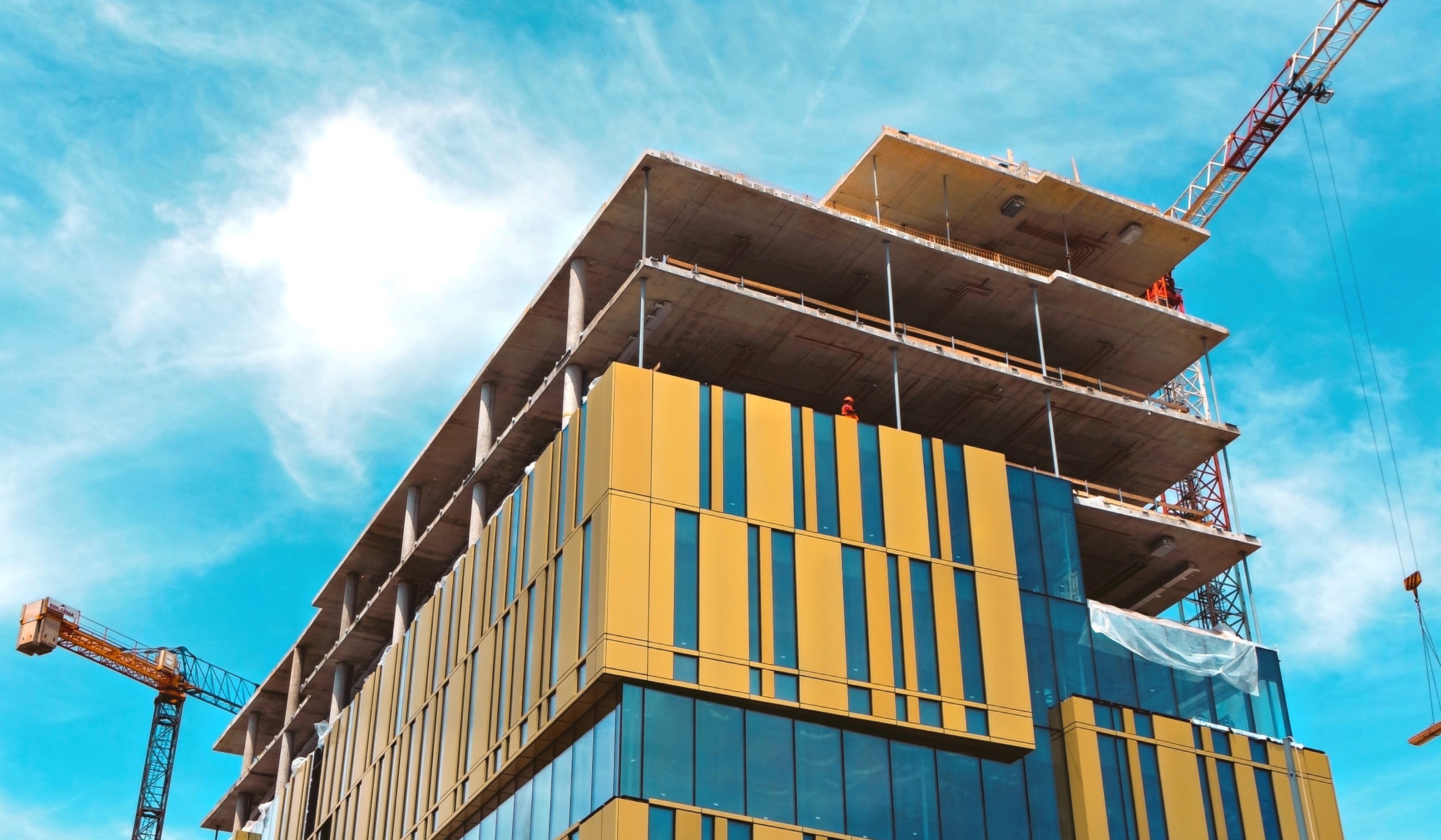 Bâtiment en construction aux façades colorées entouré de grues