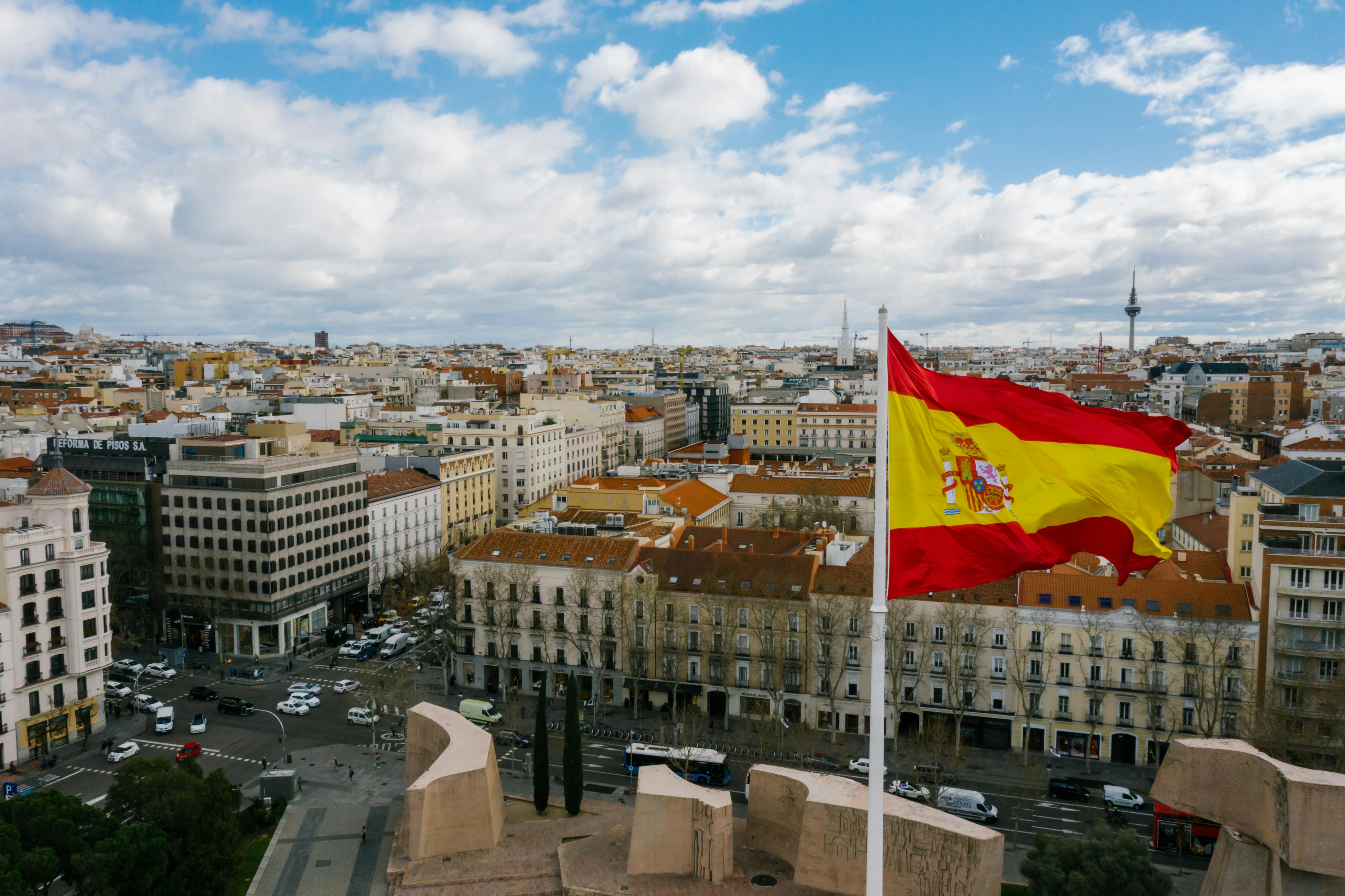 Drapeau espagnol flottant au-dessus des toits d'une grande place
