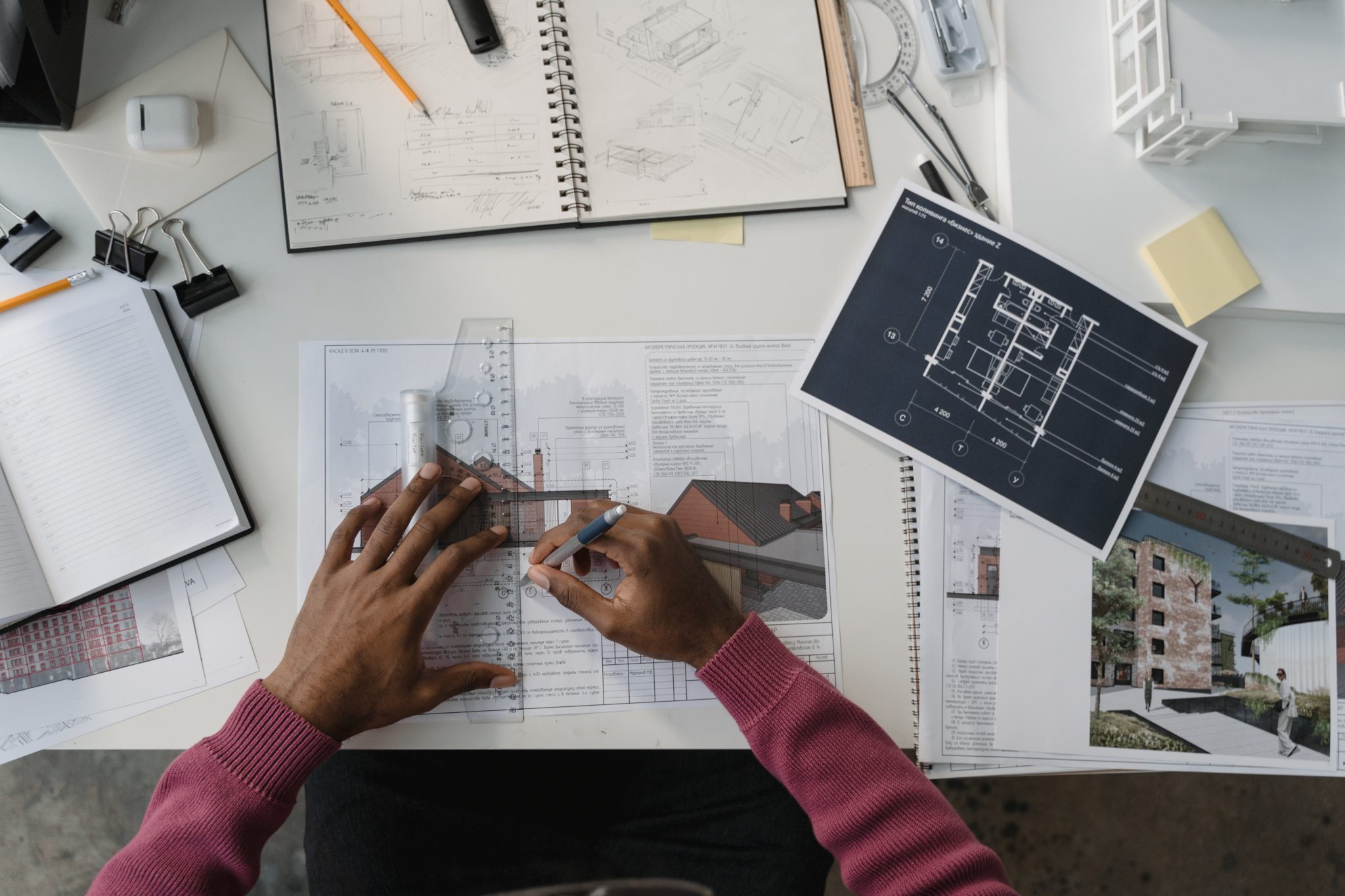 Mains d'un architecte travaillant sur des plans et un carnet de croquis