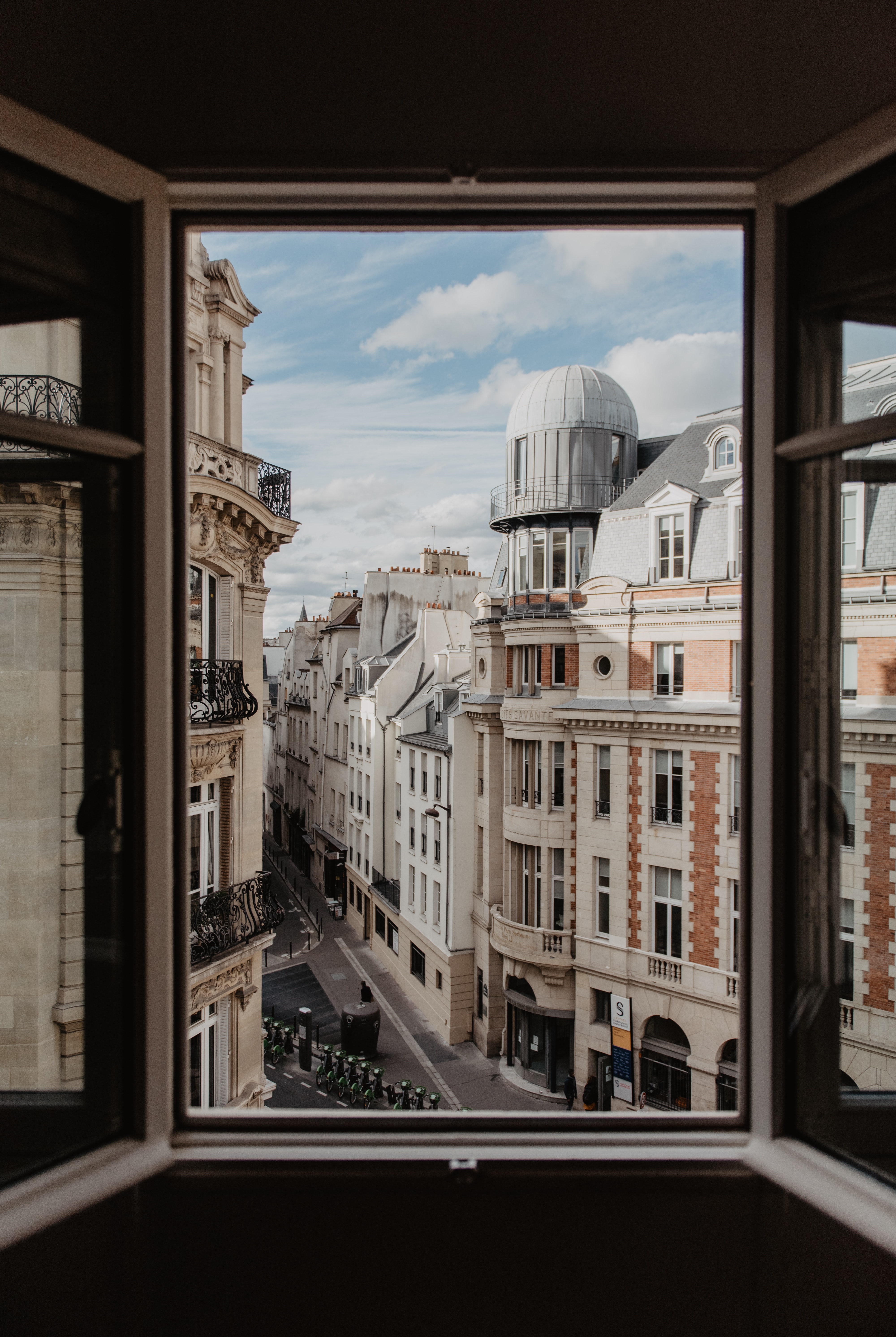 Fenêtre ouverte donnant sur une rue d'immeubles anciens