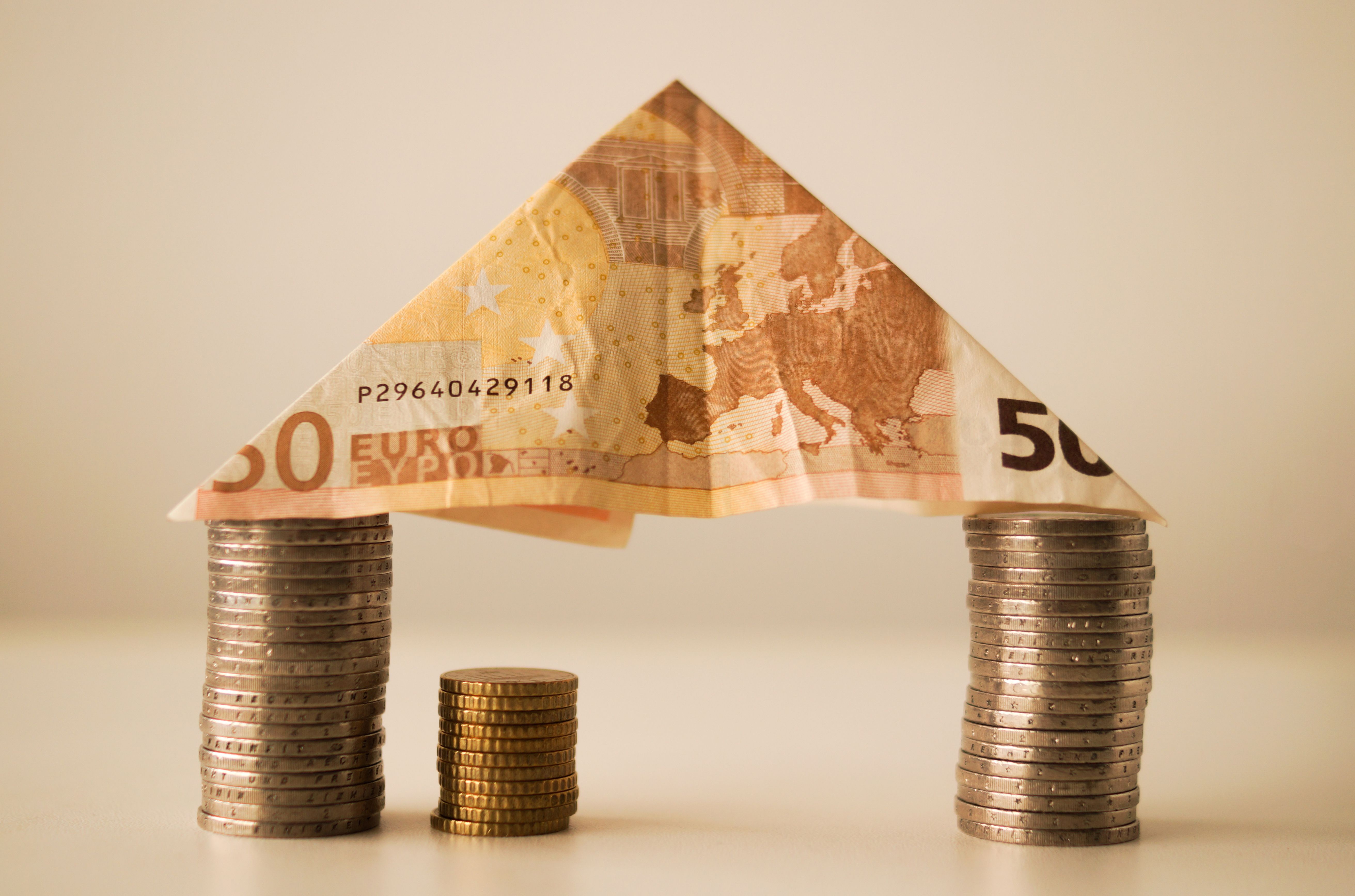 Billet de cinquante euros plié en toit au-dessus de piles de pièces