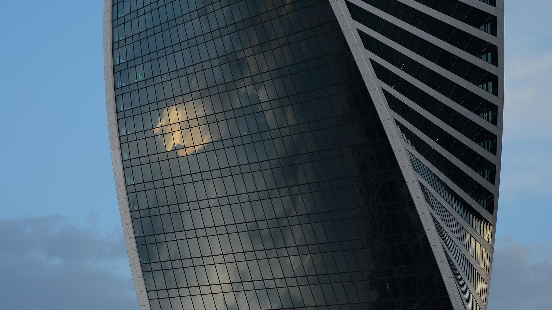 Façade courbe en verre d'une tour de bureaux se détachant sur le ciel