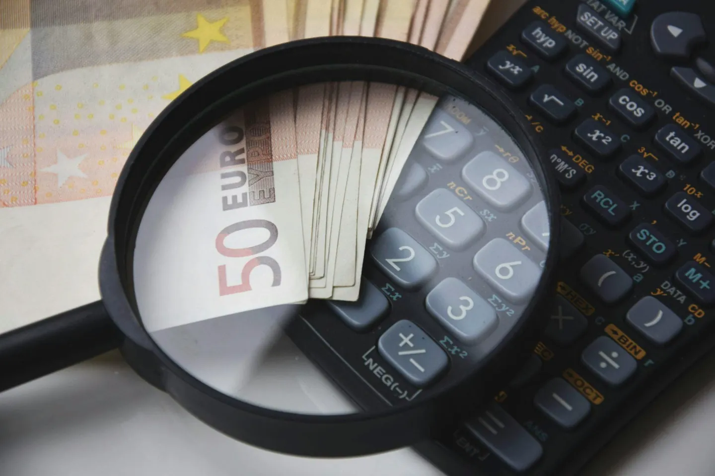 Loupe grossissant un billet de cinquante euros posé sur une calculatrice