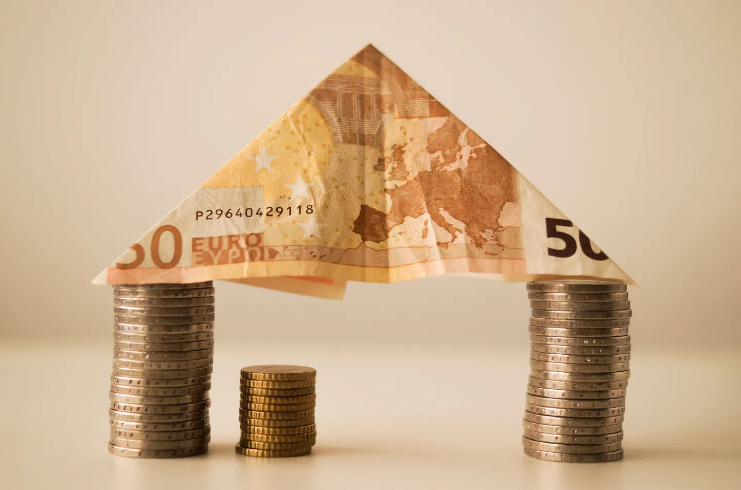 Billet de cinquante euros plié en toit au-dessus de piles de pièces
