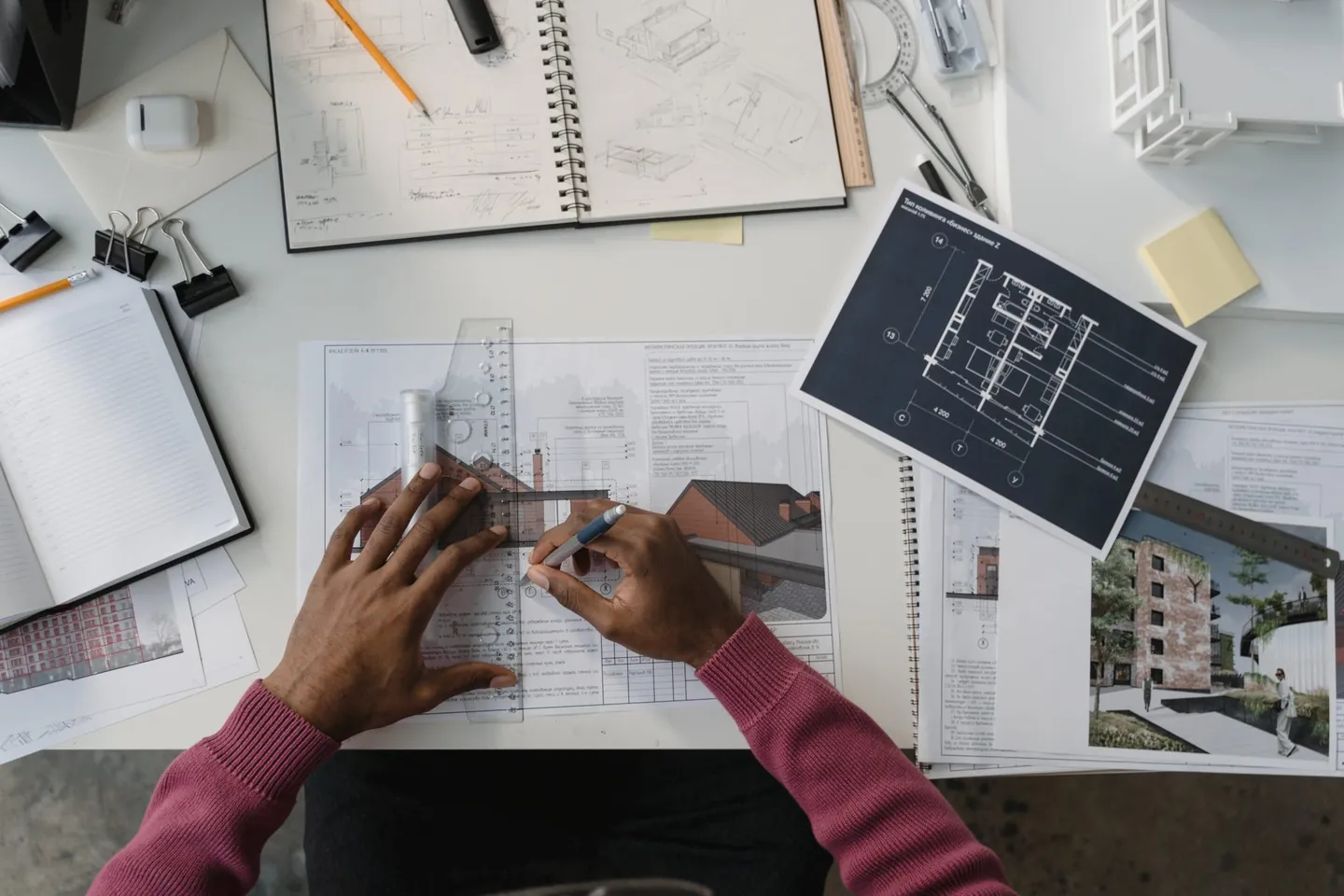 Mains d'un architecte travaillant sur des plans et un carnet de croquis