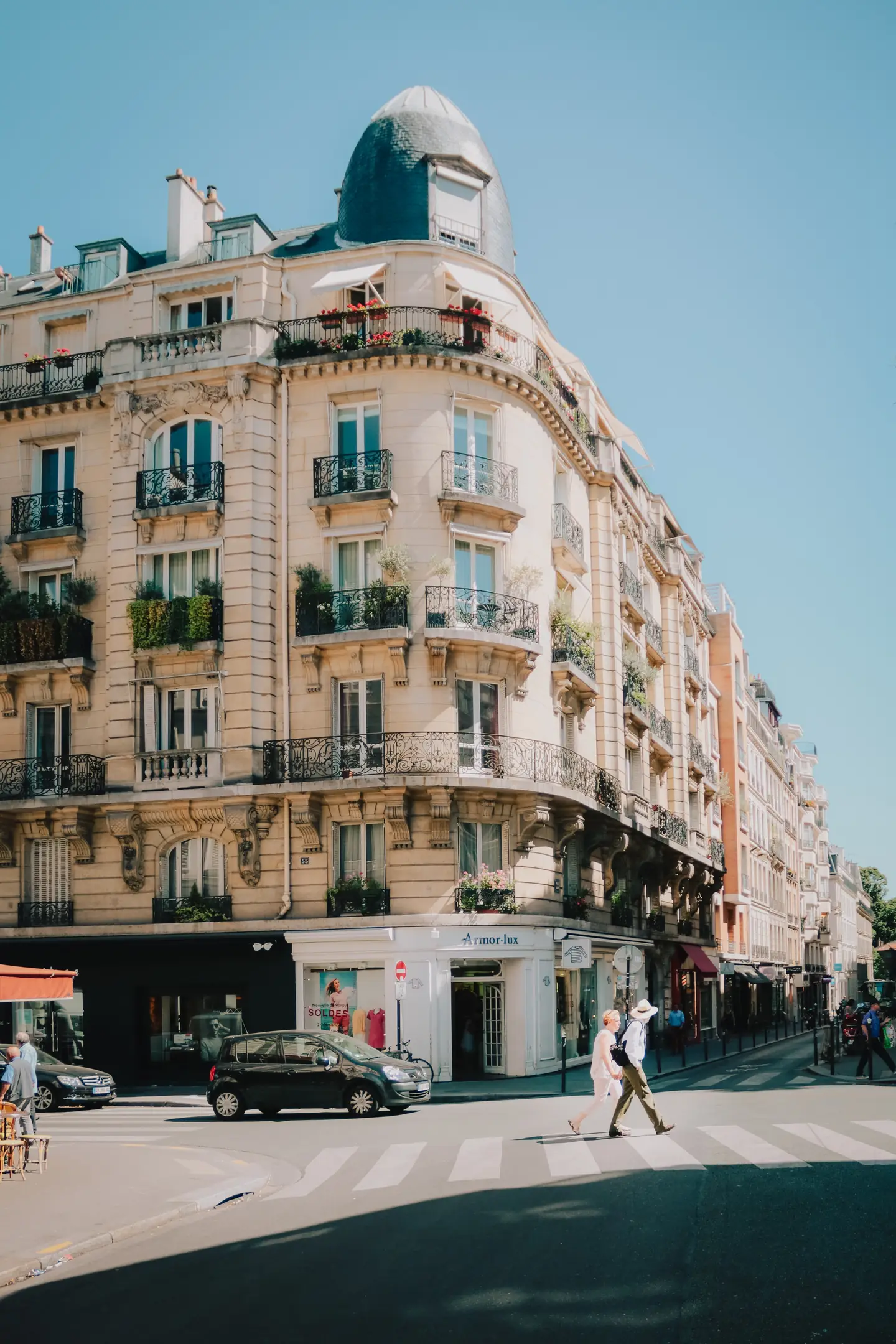 Immeuble d'angle aux façades claires dans une rue ensoleillée