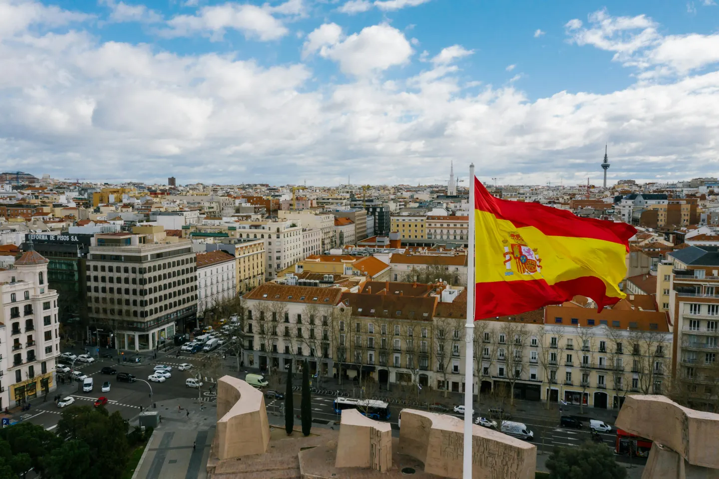 Drapeau espagnol flottant au-dessus des toits d'une grande place