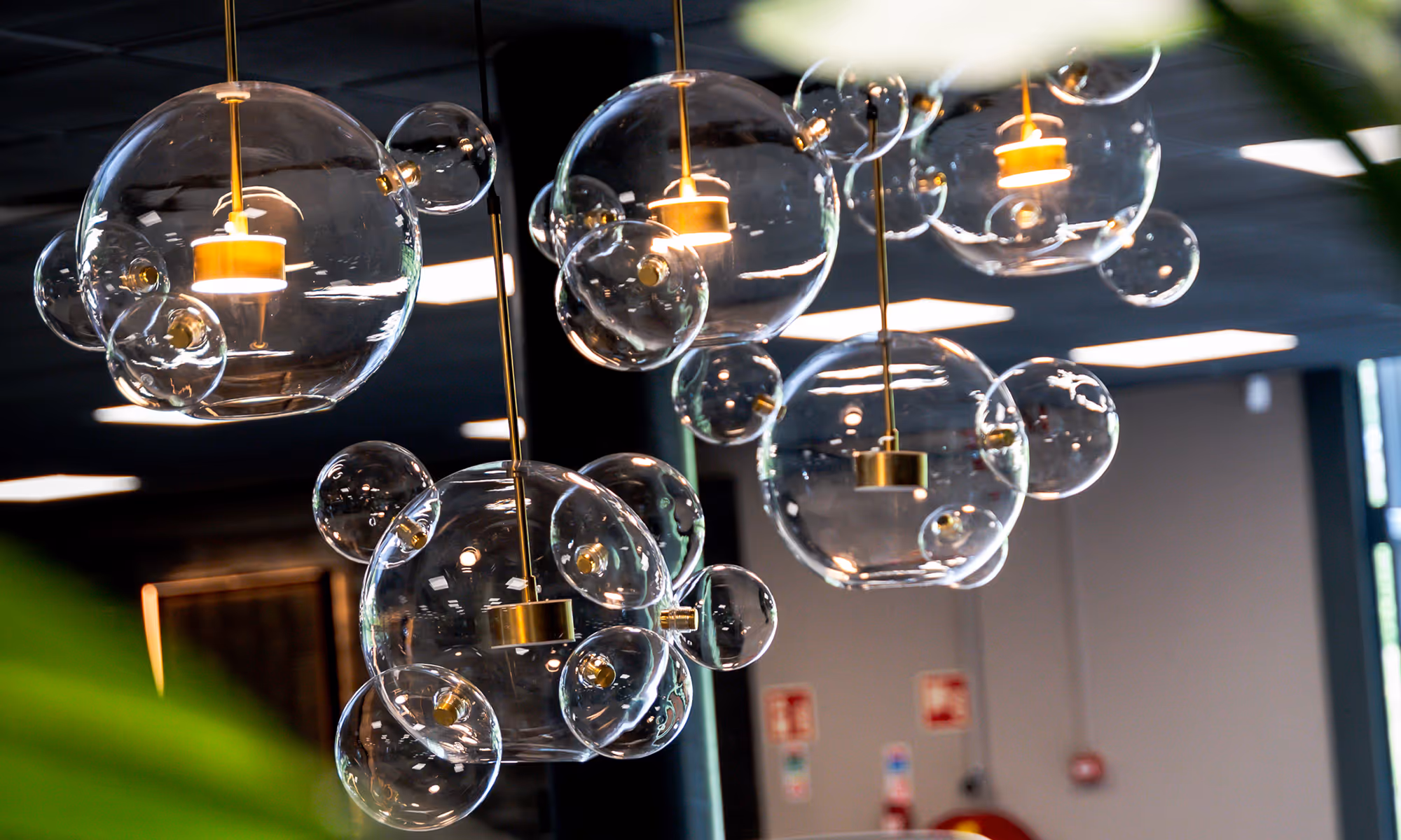 Moderne hanglampen met glazen bollen die aan gouden stangen hangen in een binnenruimte.
