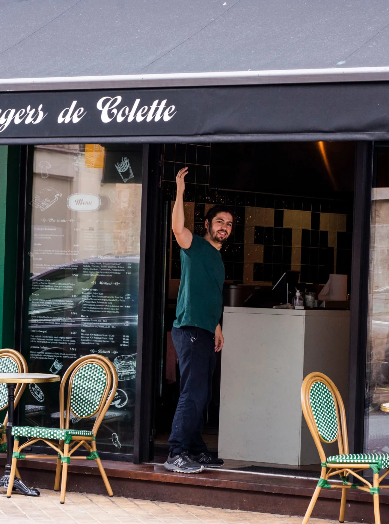Un employé du restaurant des Chartons qui fait un signe de la main devant le restaurant les Burgers de Colette à Bordeaux aux Chartrons