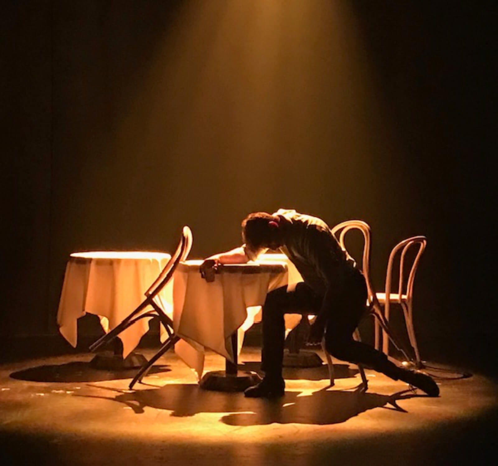 John Marcher played by Tony Yazbeck in the "Waltz Melancolique" scene from The Beast in the Jungle. Tony Yazbeck hunched over a table in dim lighting.