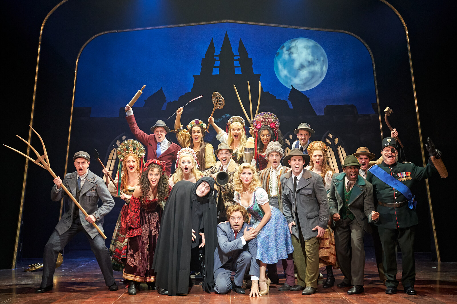 Group photo of the West End company of Young Frankenstein. All are in character for the finale of Act One: looking in the distance as the Monster escapes.