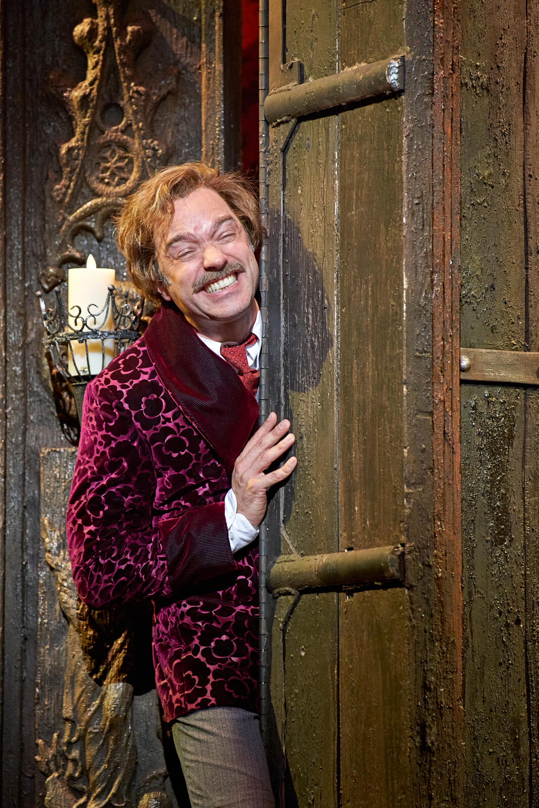 Dr. Frankenstein (Hadley Fraser) trapped as the revolving bookcase closes on his body. He makes a painful face.