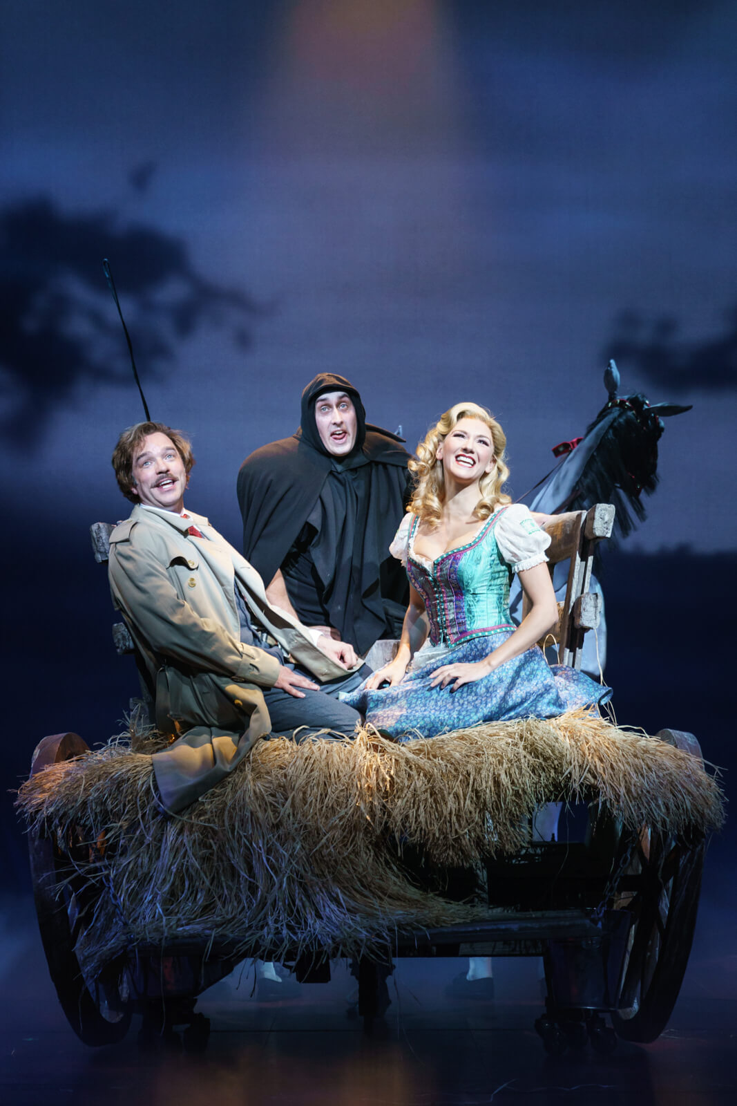 Dr. Frankenstein (Hadley Fraser), Igor (Ross Noble), and Inga (Summer Strallen) sing "Roll in the Hay," having a good time at the back of a horse-drawn carriage full of hay.