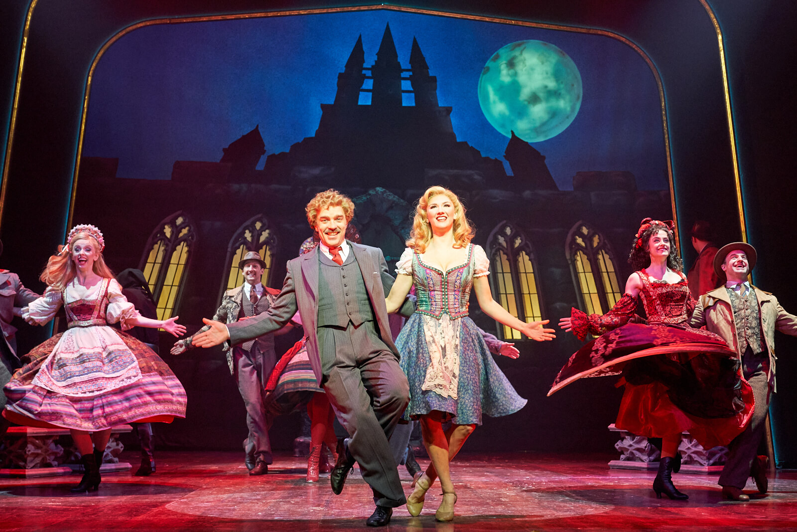 Dr. Frankenstein (Hadley Fraser) and Inga (Summer Strallen) happily dancing under a full moon in front of the castle with The Villagers to the song "Transylvania Mania" in Young Frankenstein West End. 