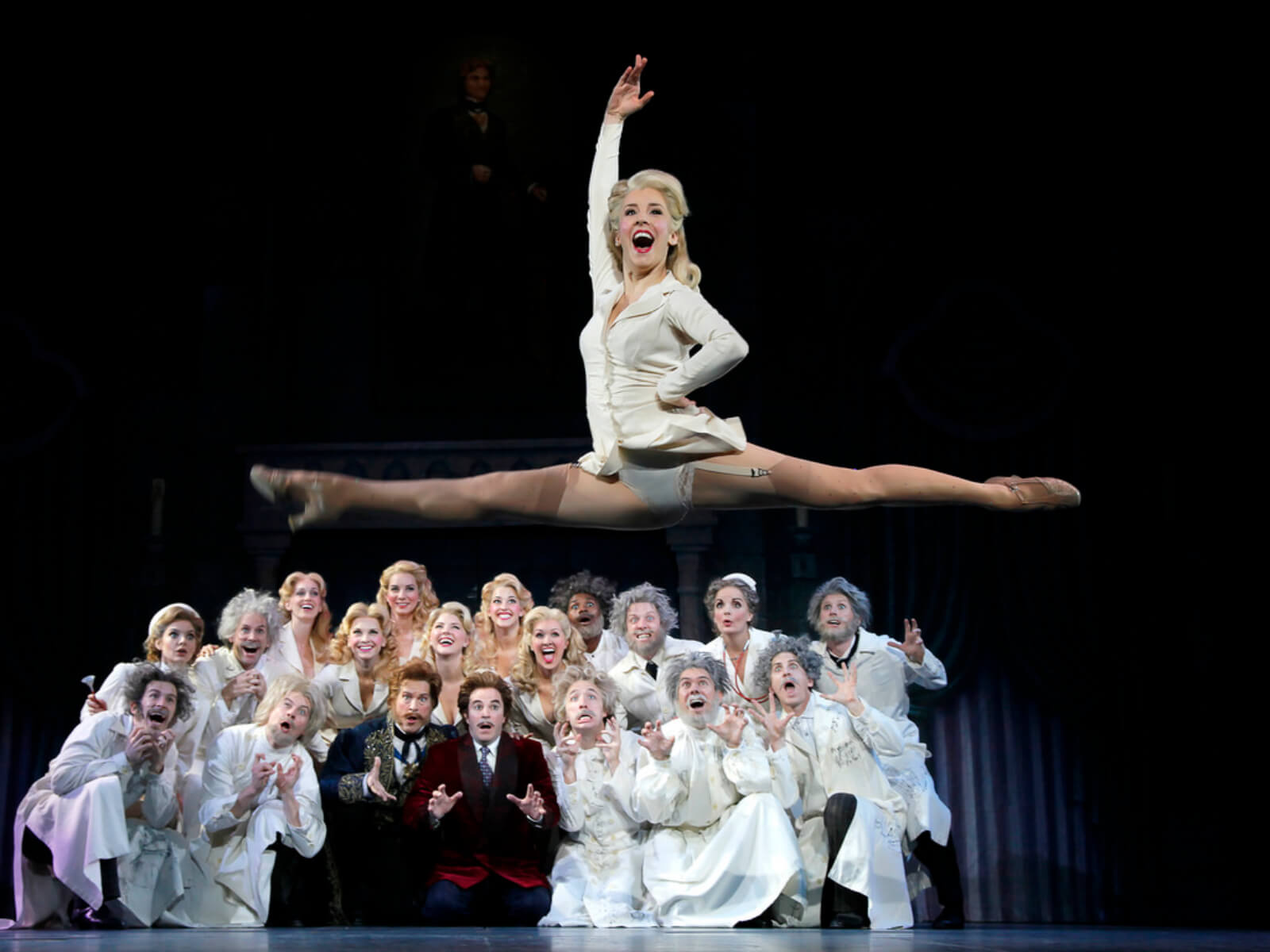 Lab Assistant (Brittany Marcin Maschmeyer) jetes high above the cast of Young Frankenstein. They are all singing "Join the Family Business' and dressed as Dr. Frankensteins ancestors.