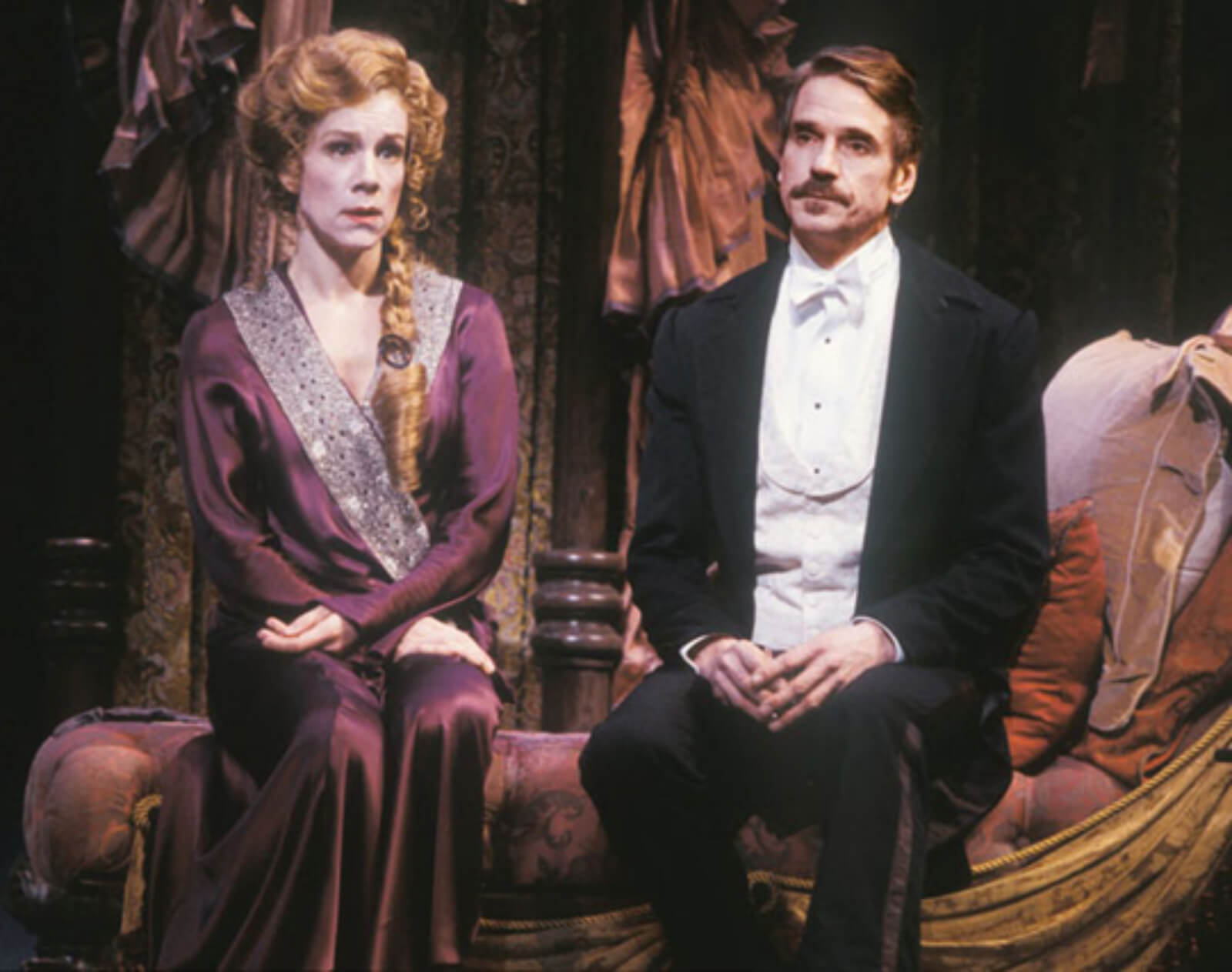 Juliet Stevenson as Desiree Armfeldt and Jeremy Irons as Fredrik Egerman sing "You Must Meet My Wife". She is dressed in her purple dressing gown and he is in a white tie and tails. They sit on a divan in A Little Night Music.