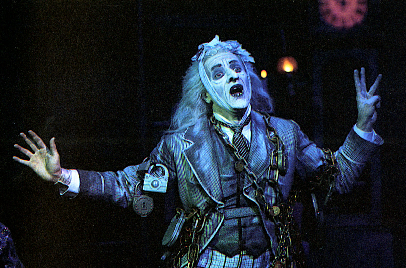 The Ghost of Jacob Marley (Jeff Keller) appears and is wrapped in chains with candlelight in the background.