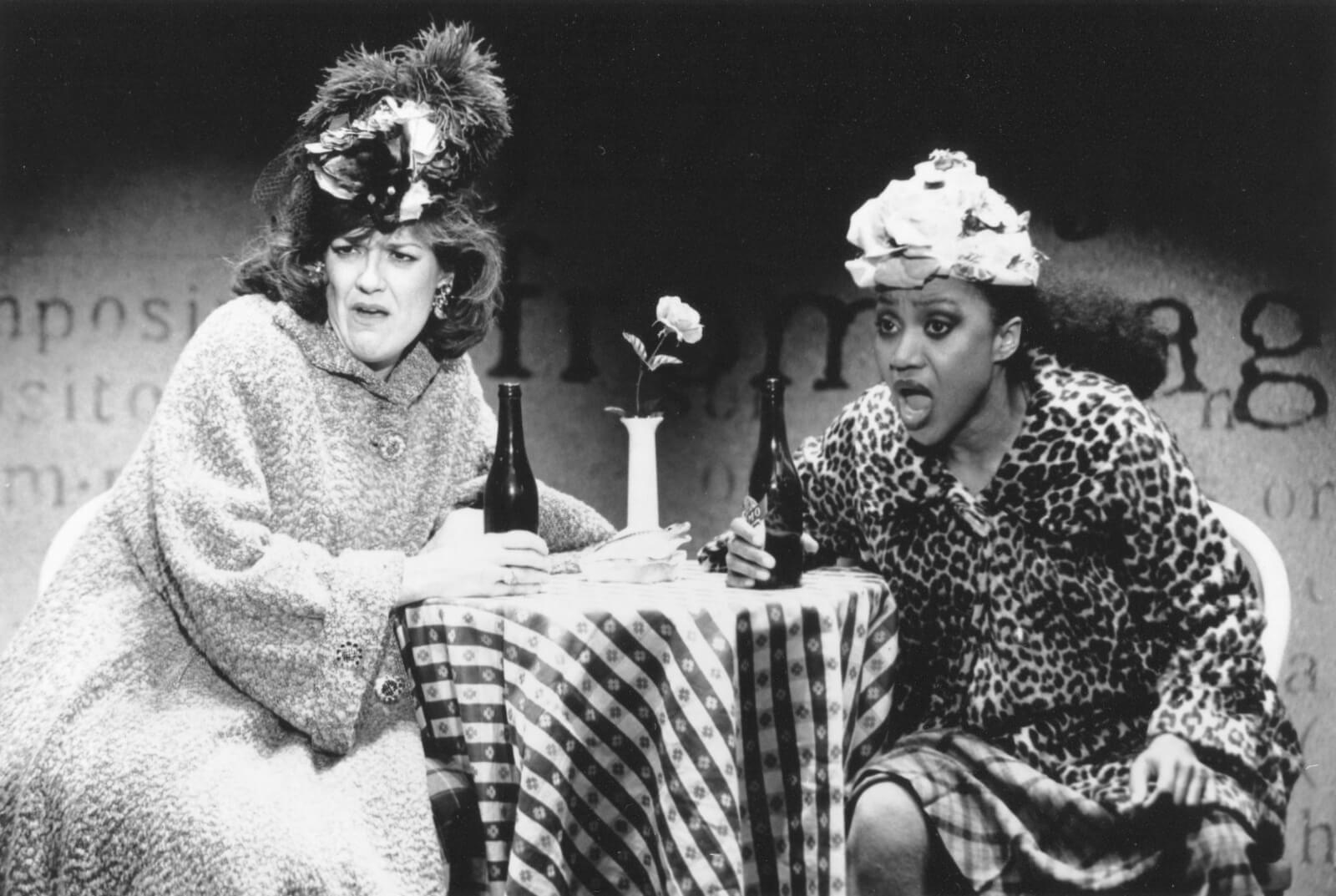 Karen Mason and Brenda Pressley sitting at a table in large hats and fur coats