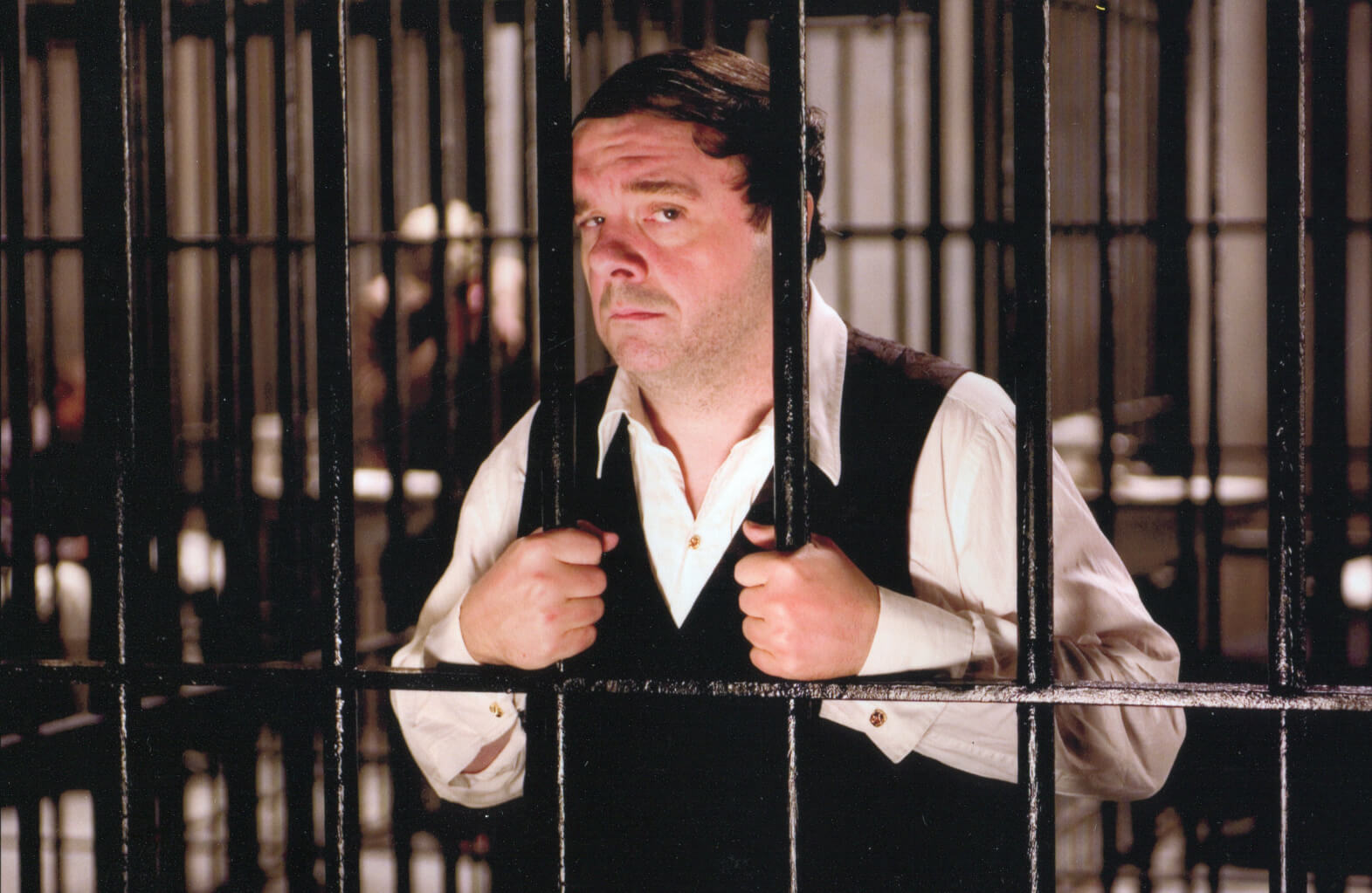 Max Bialystock (Nathan Lane) looking very disappointed behind bars. He is singing "Betrayed". 