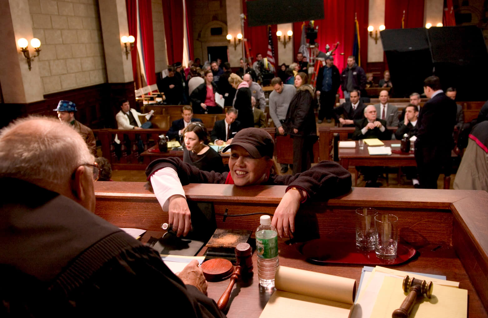 Susan Stroman and Judge (David Huddleston) rehearse the court room scene. Stro is giving direction. The court room scene is populated and is in full action. 