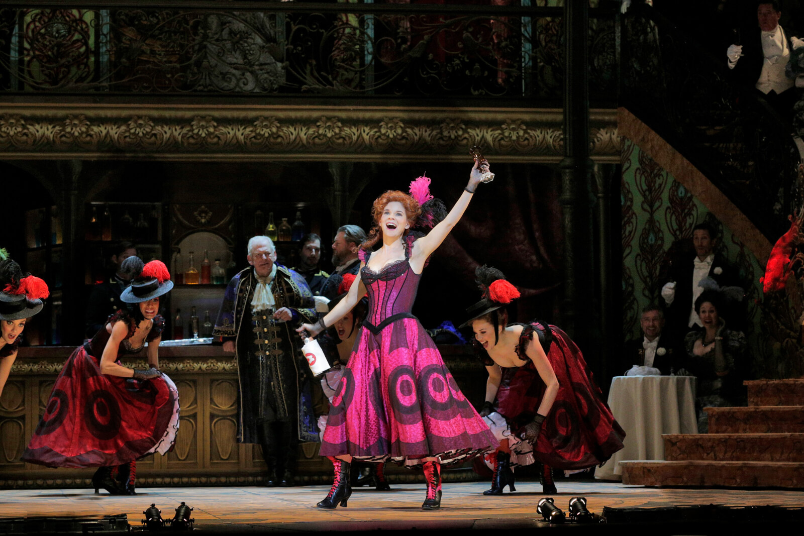 Valencienne (Kelli O'Hara) performing "We're the Ladies of the Chorus". She is in a Magenta Can Can dress singing with a bottle of wine. 