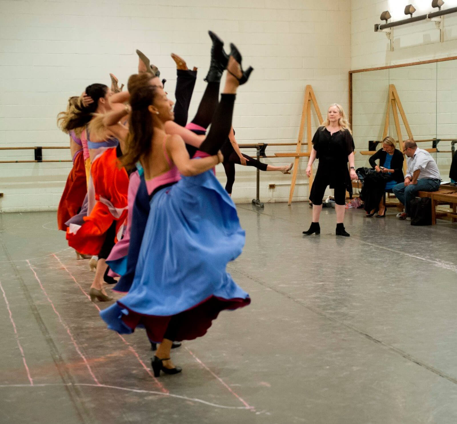 Susan Stroman with the Female dancers rehearsing the "Can Can". The ladies stand in a line kicking with one leg high in the air.