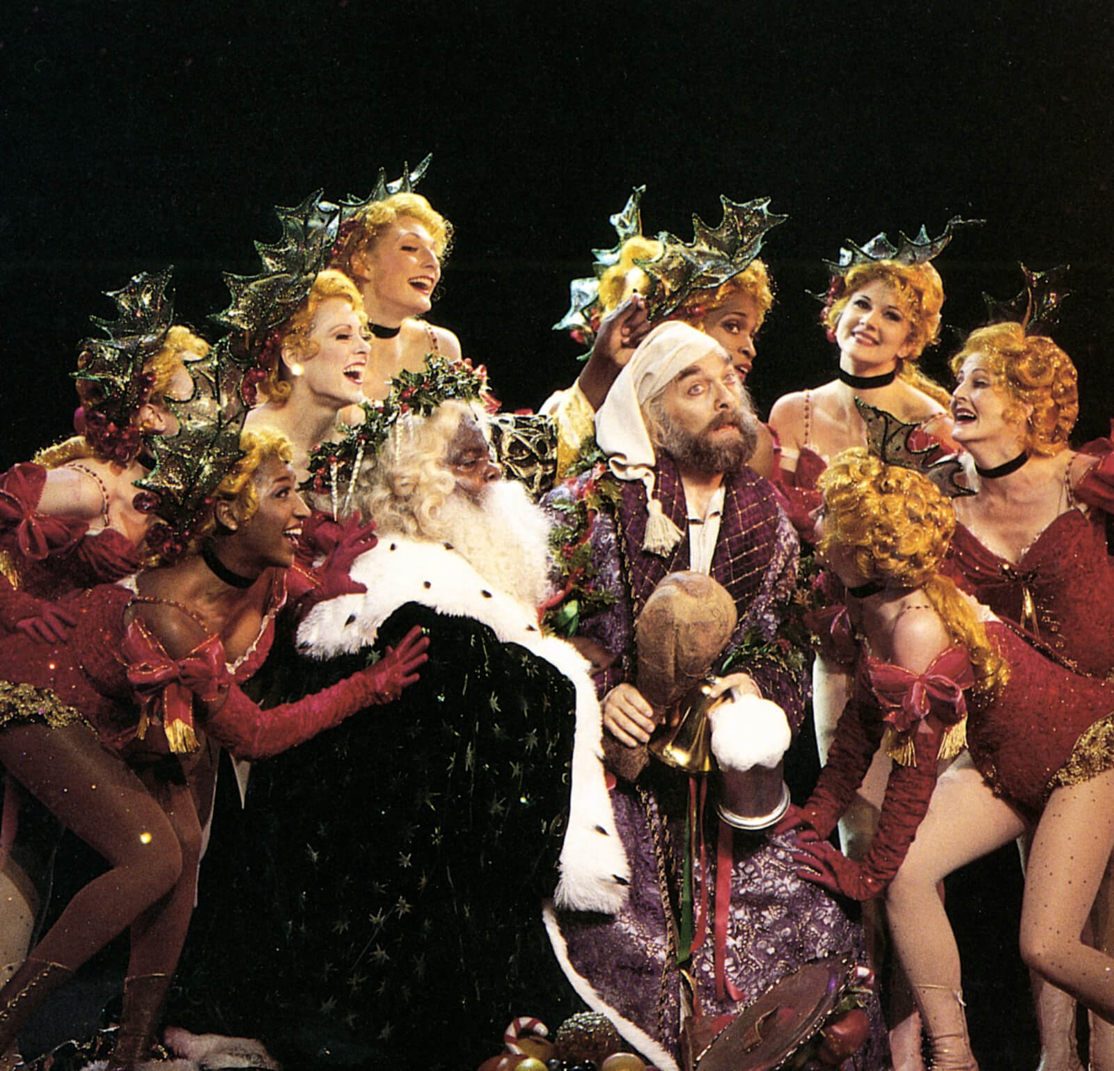The Holly Girls gather around Scrooge (Walter Charles) and The Ghost of Christmas Present (Michael Mandell) in "Abundance and Charity".