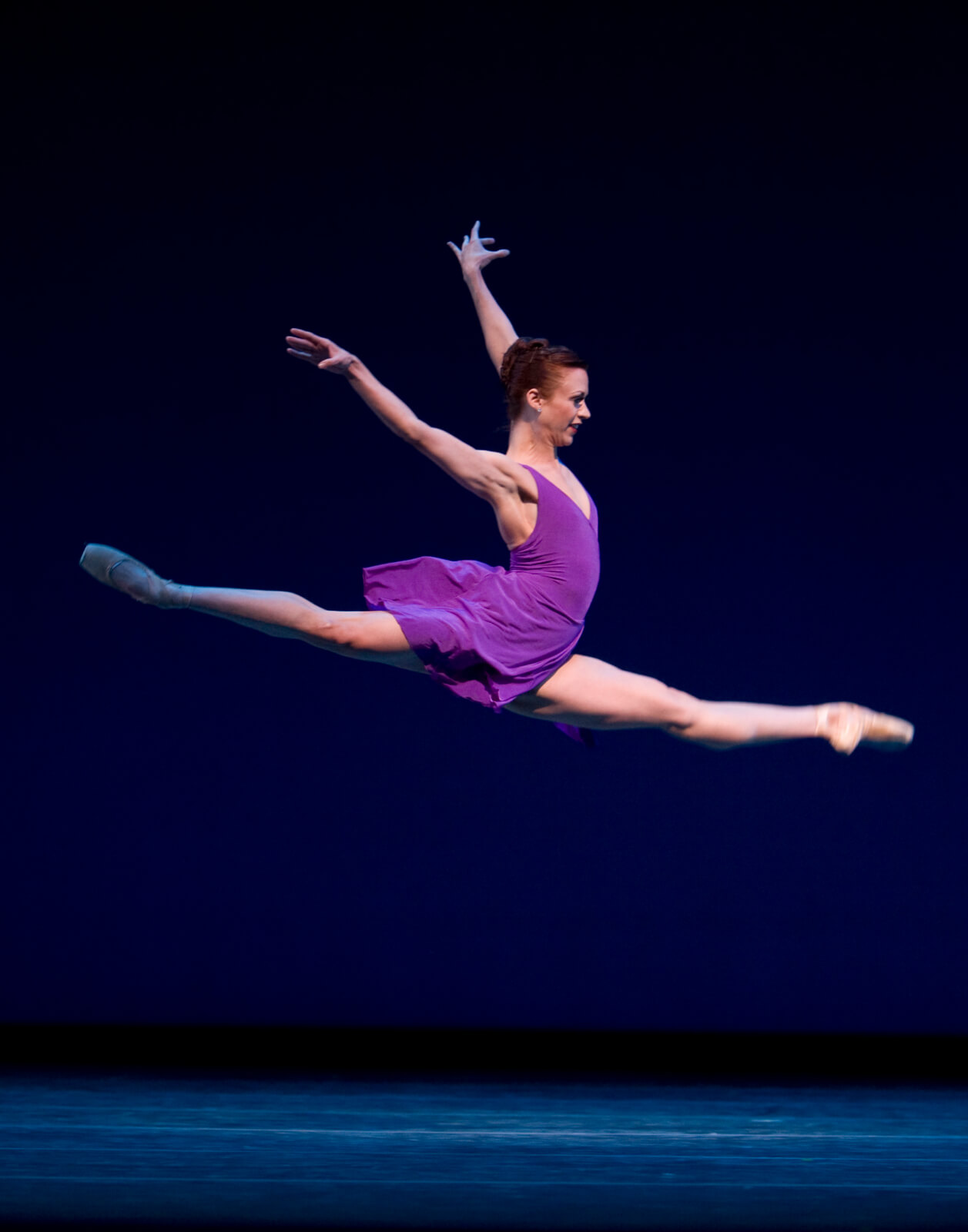 Lesley Rausch in violet dress doing an a perfect jete.