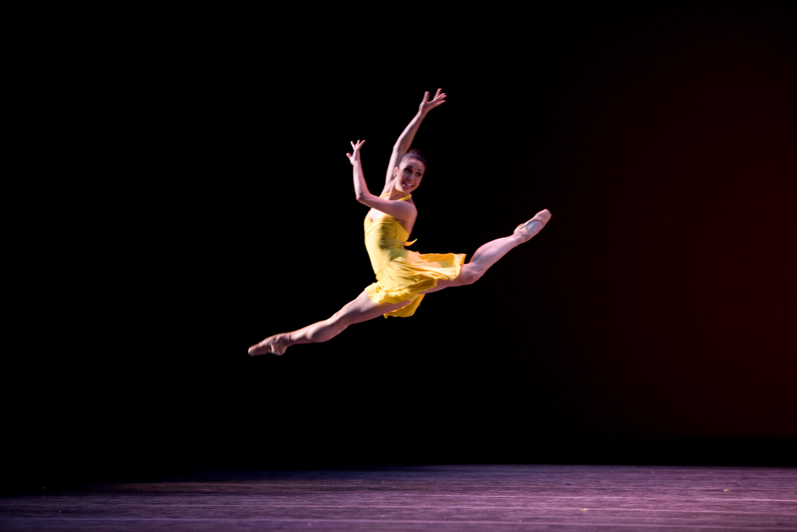 Noelani Pantastico in a beautiful yellow dress doing a perfect jete.