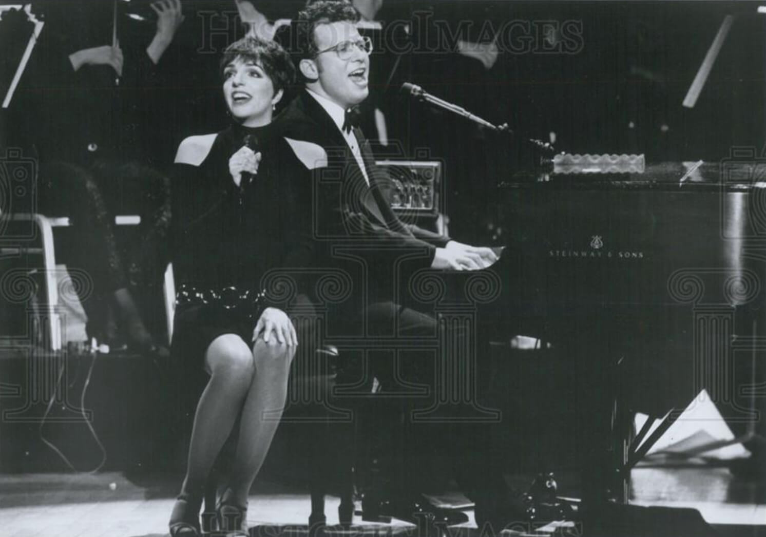 A black and white photo of Liza Minnelli singing with Billy Stritch beside the piano.