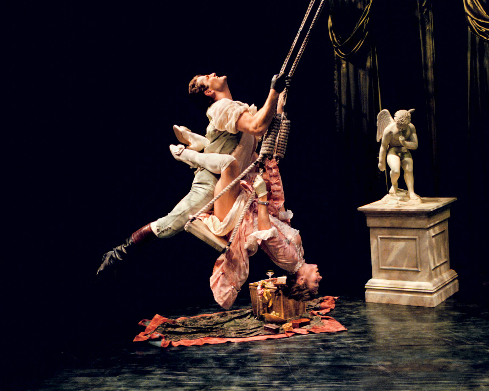 Frenchmen (Seán Martin Hingston) and Girl on a Swing (Stephanie Michels) are blissfully intertwined on moving swing.