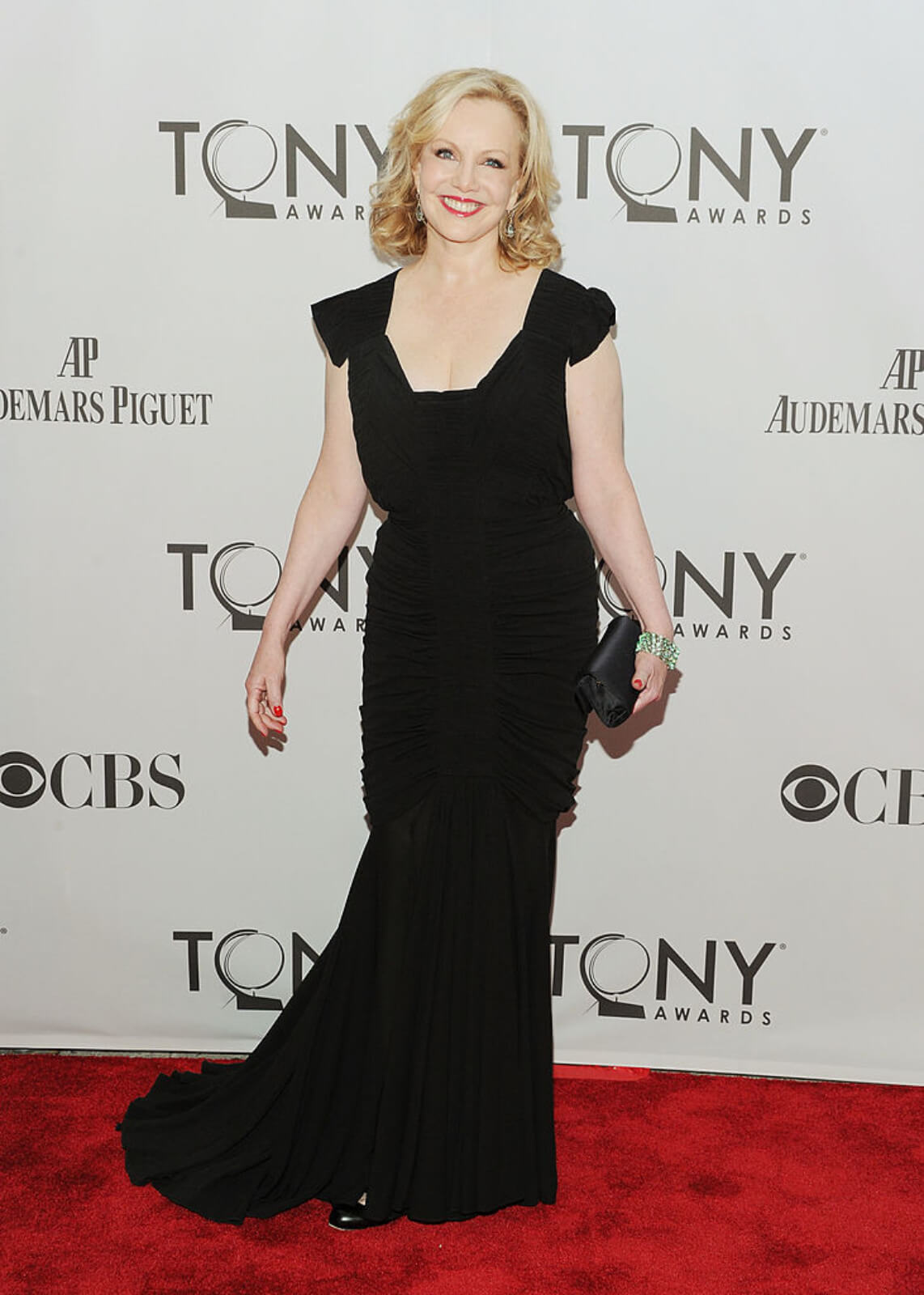Portrait of Susan Stroman on the red carpet at the Tony Awards in a black dress, smiling with a clutch in her left hand.