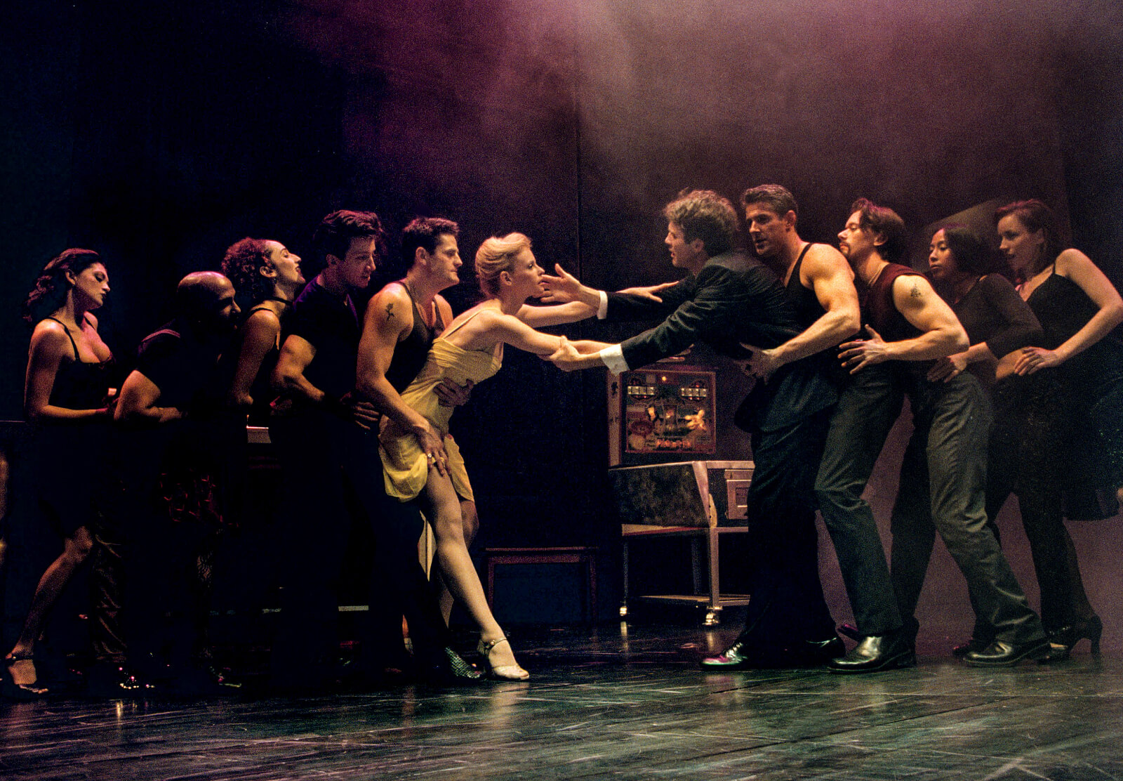 Girl in the Yellow Dress (Deborah Yates) and Michael Wiley (Boyd Gaines) reach for one another as they are pulled apart by the club-goers in a line.