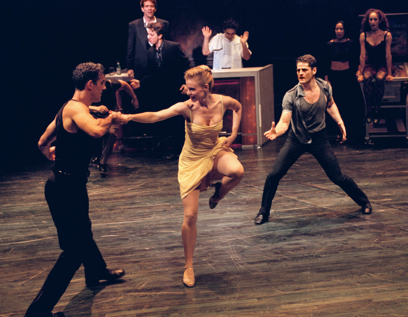 Girl in the Yellow Dress (Deborah Yates) holds the hand of clubgoer, Jack (Jack Hayes), while Johnny (Sean Martin Hingston) also offers his hand while standing behind the couple.