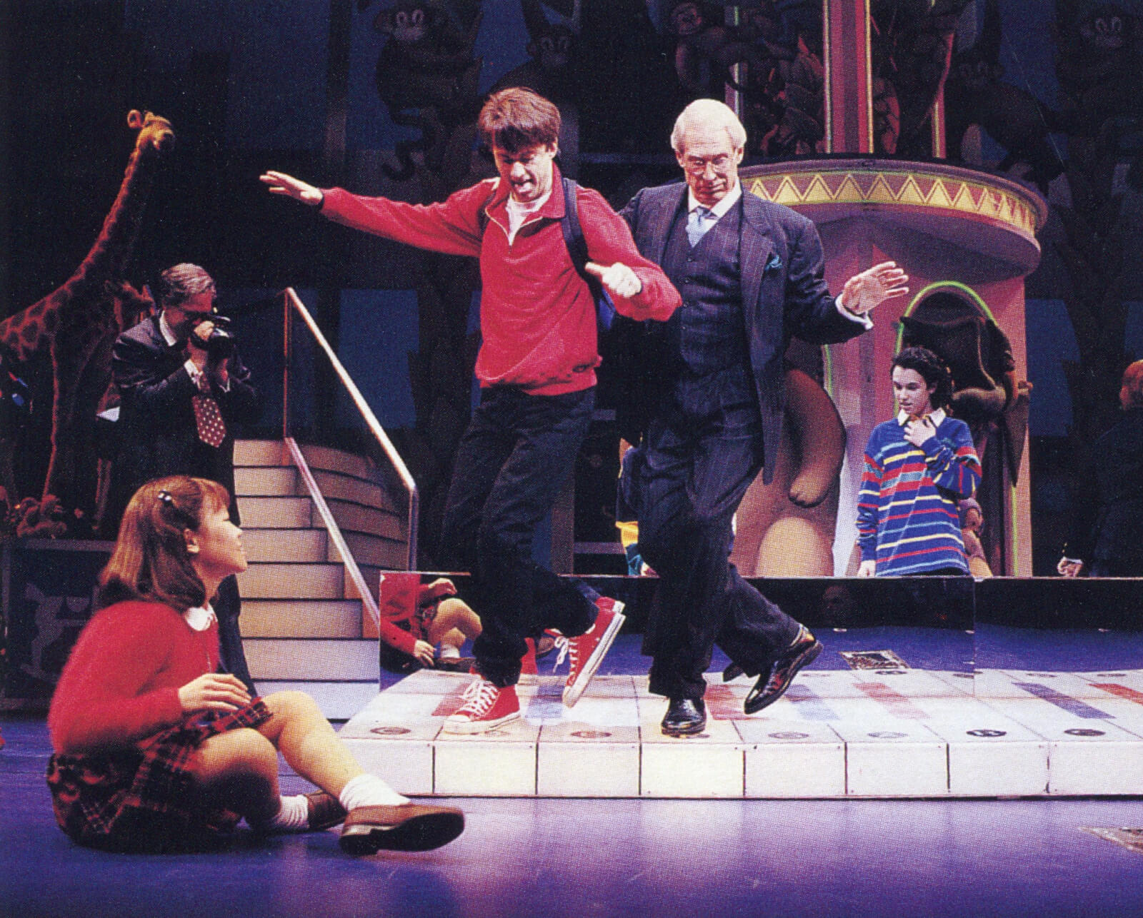 Josh (Daniel Jenkins) and MacMillan (John Cypher) dance on the big piano keyboard.
