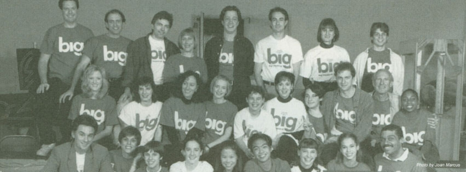 A black and white photo of the full company of the Big The Musical in official merchandise shirts