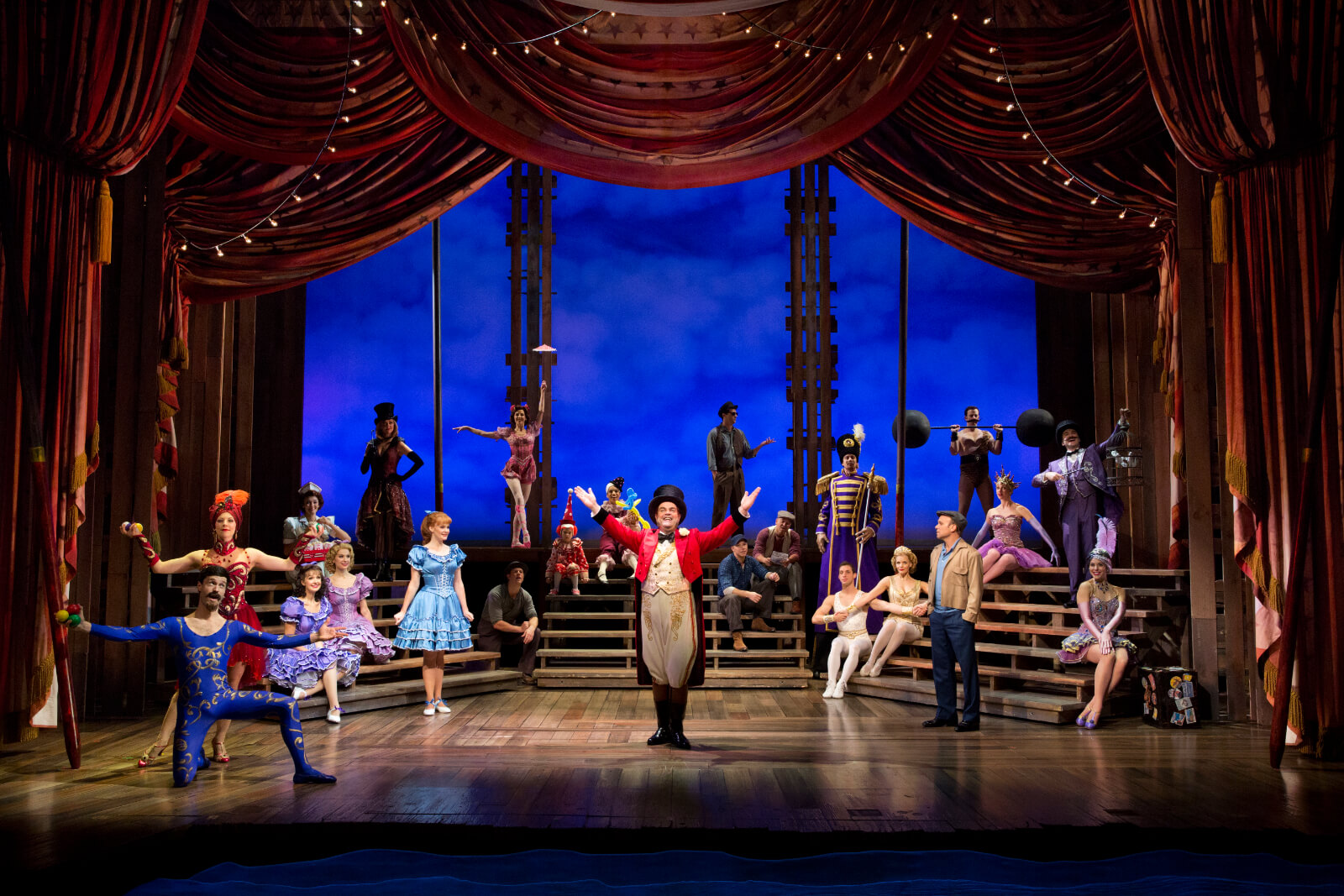 Amos Calloway (Brad Oscar) with the ensemble in the Calloway circus. The ensemble cast on risers in a circus scene with a ringmaster in the center