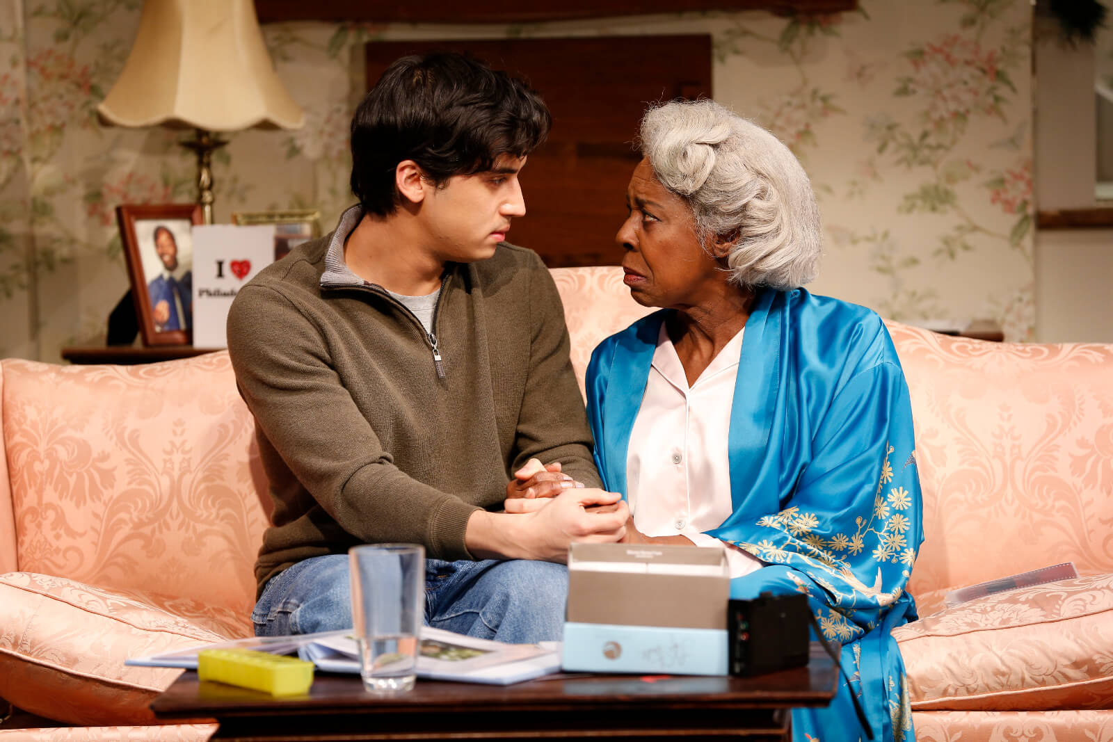 Fidel (Michael Rosen) and Dotty (Marjorie Johnson) sit closely on the couch while holding each other's hands on their laps