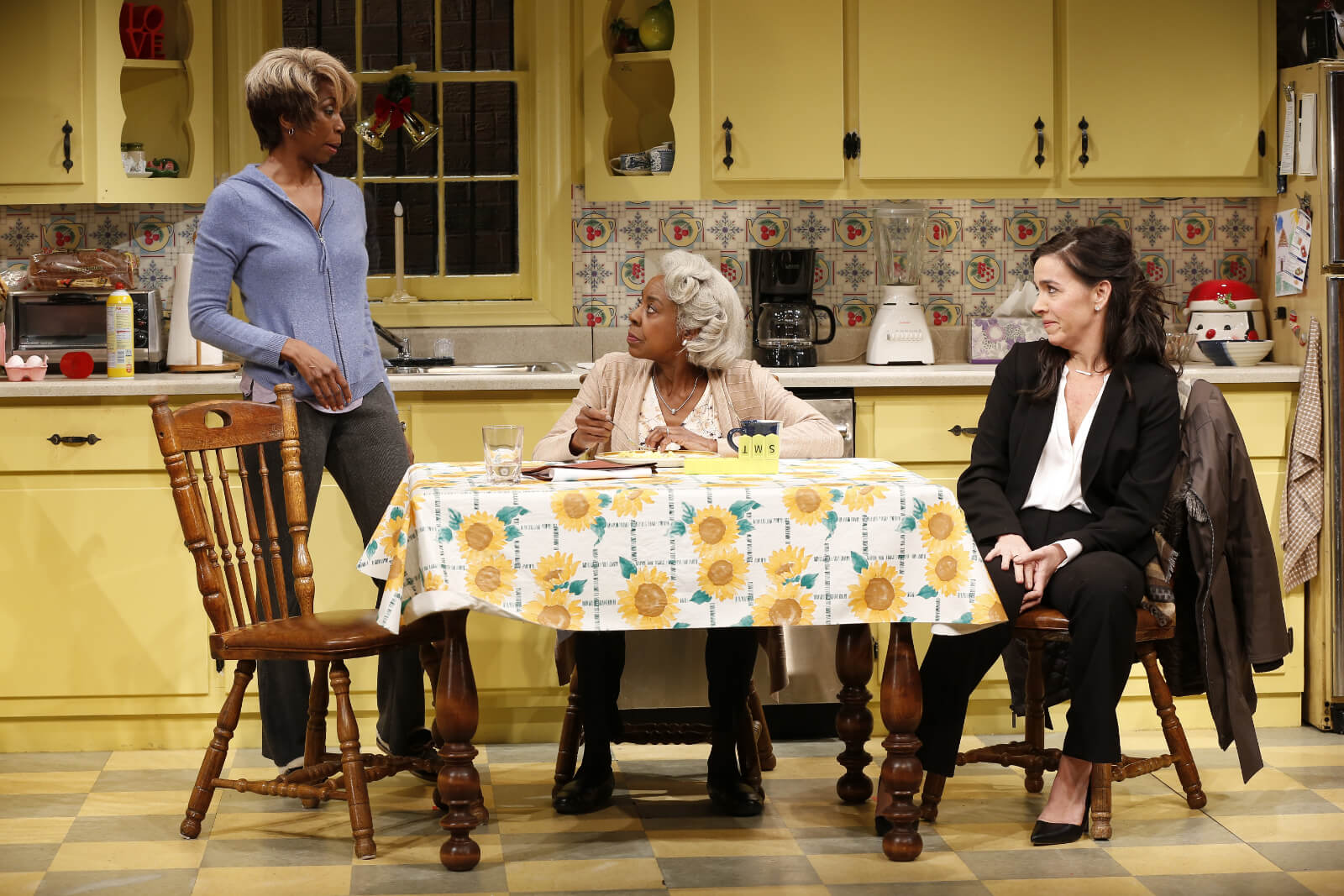 Shelly (Sharon Washington) stands in the kitchen while talking to Dotty (Marjorie Johnson) and Jackie (Finnerty Steeves) at the table