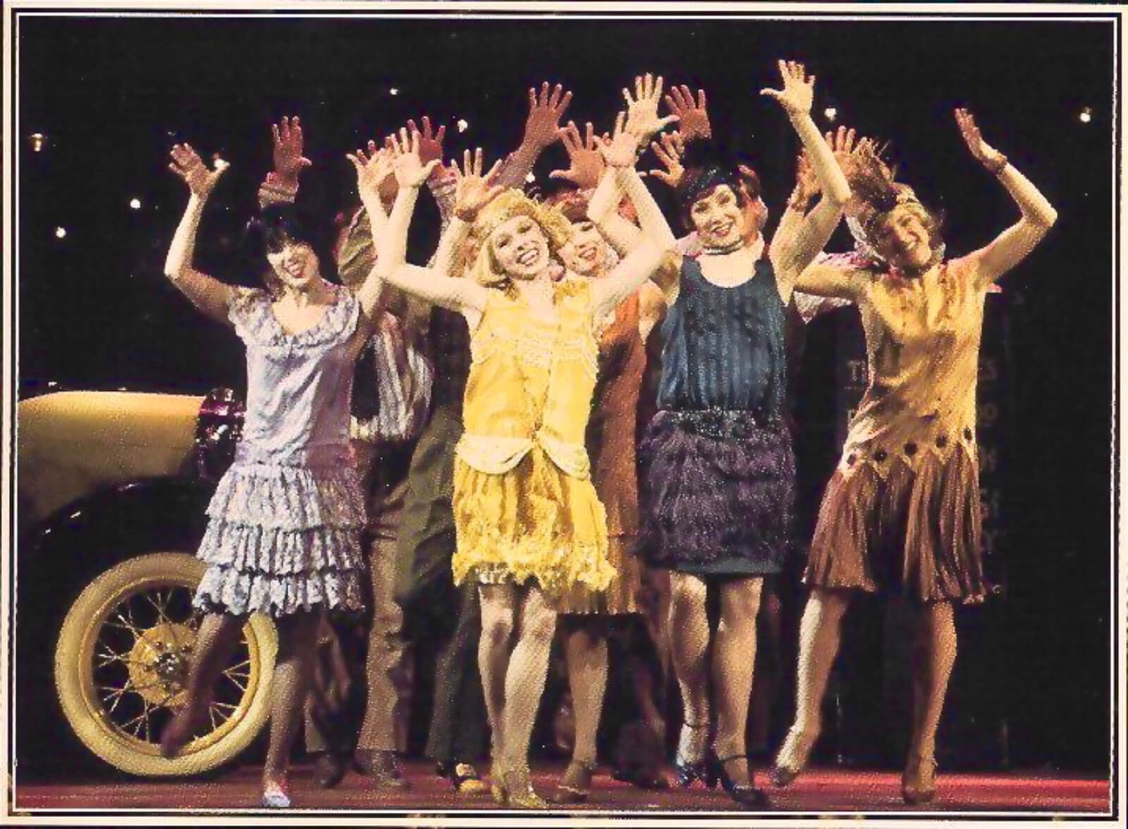 Kim (Tammy Amerson)and the beautiful ladies dancing the Charleston dancing in their elegant outfits, with arms up in the air, waving happily.