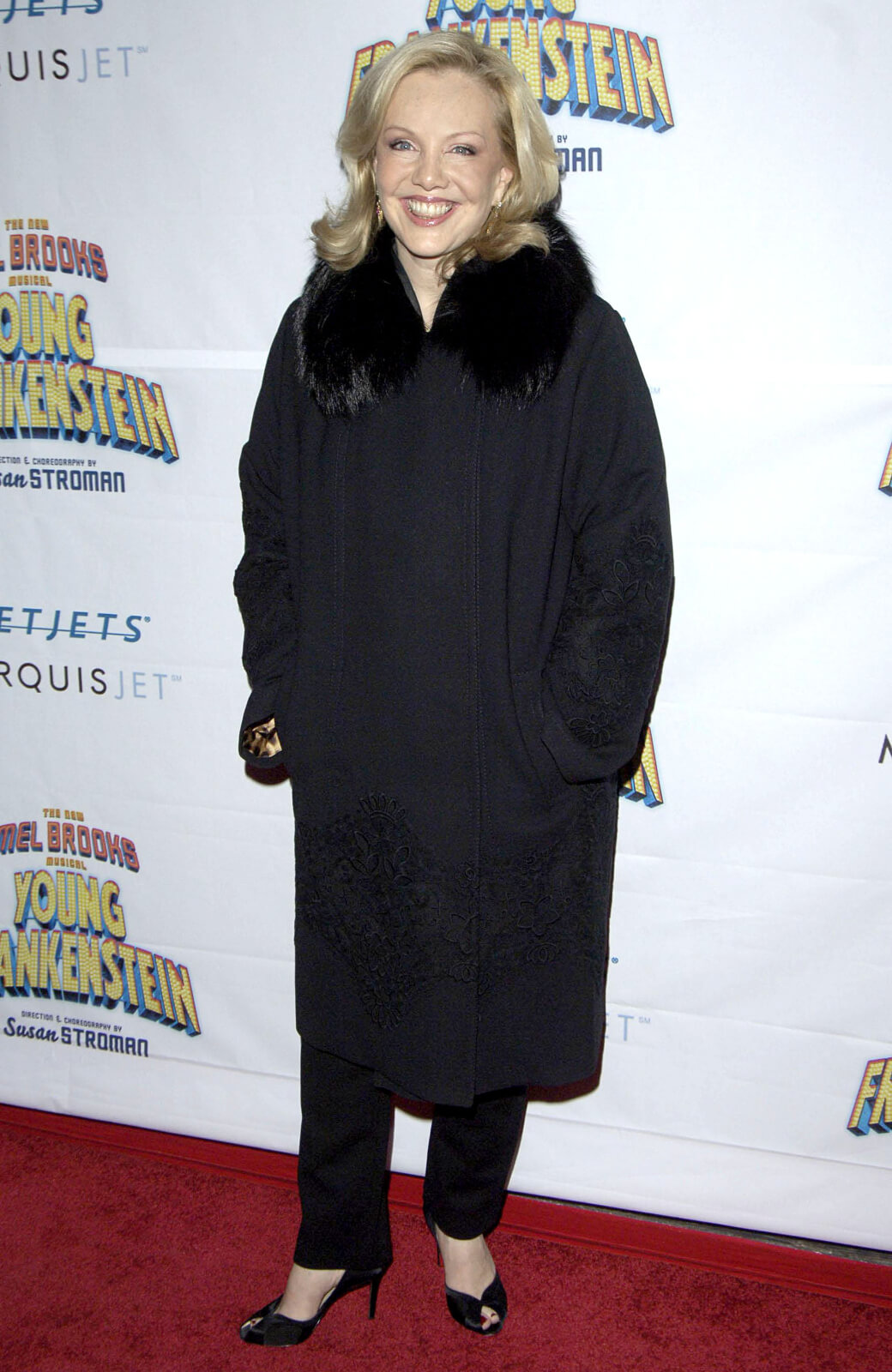 Susan Stroman on the red carpet at the opening night of Young Frankenstein, wearing black heels, pants, and jacket.
