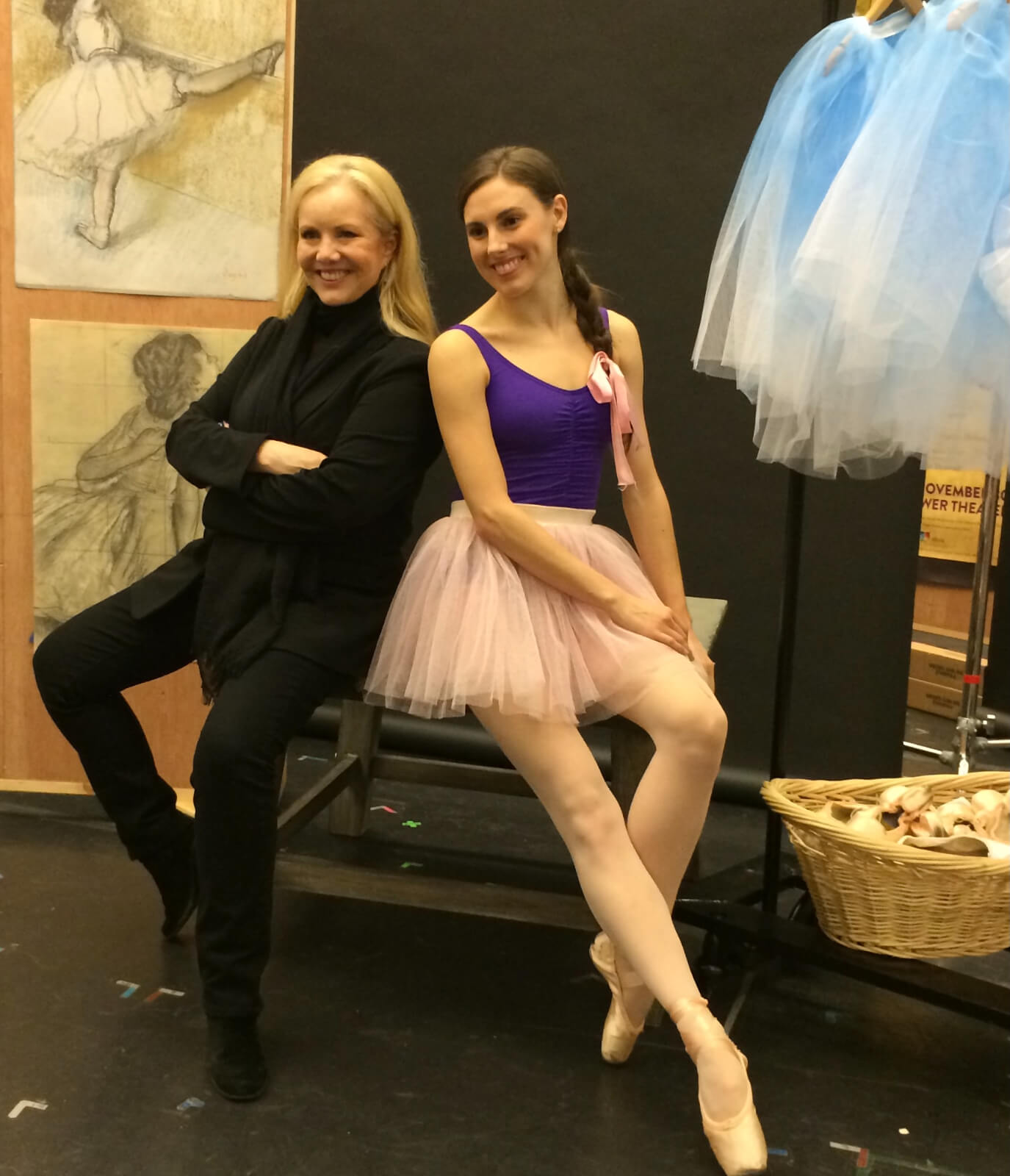 Stro and Tiler Peck, both seated and posing for Little Dancer press photos. Tiler is in a tutu while Stro is in her signature blacks.