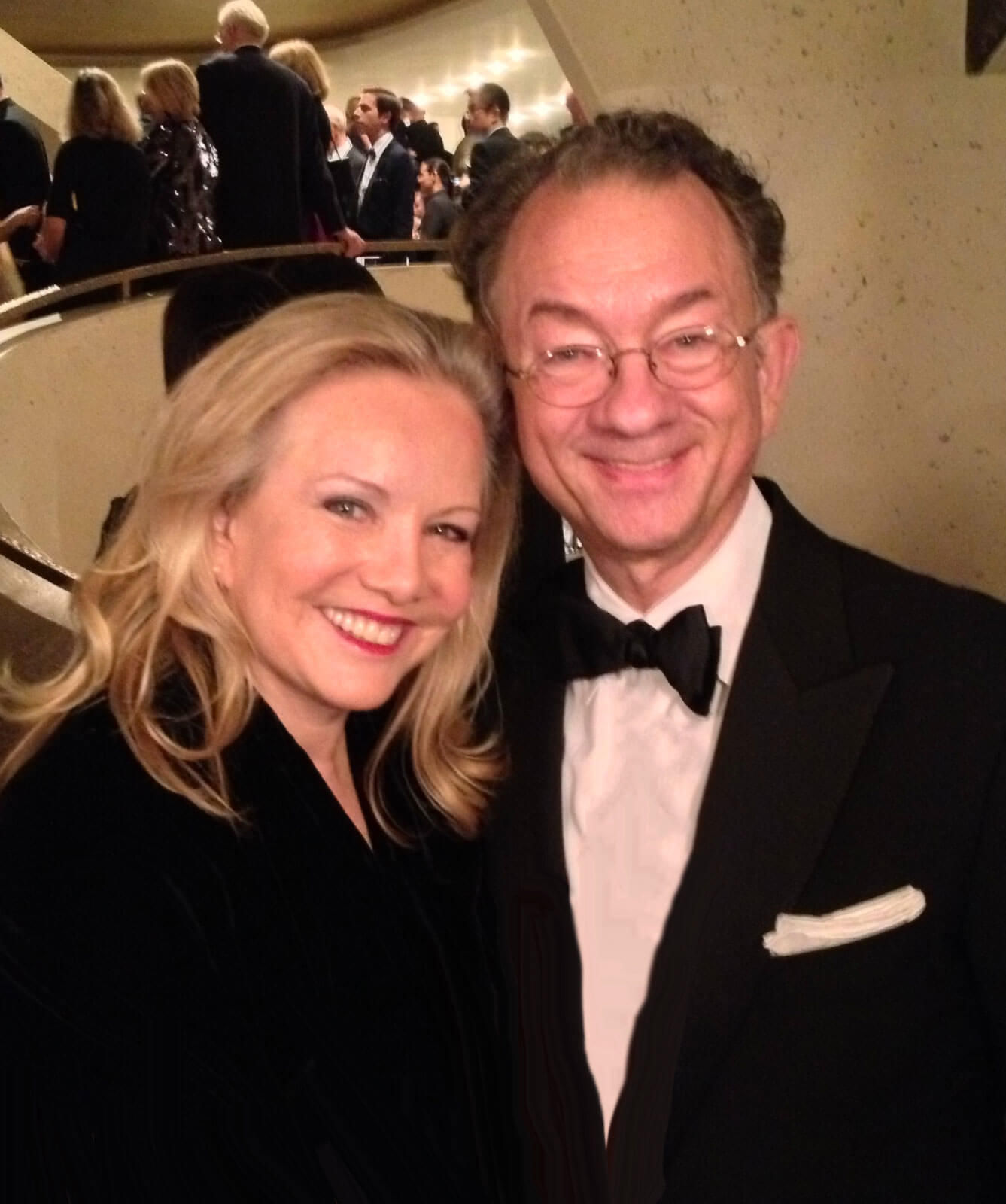 Susan Stroman with long-time collaborator, William Ivey Long. Both are in black tie and audience members can be seen in the background entering or exiting a performance.
