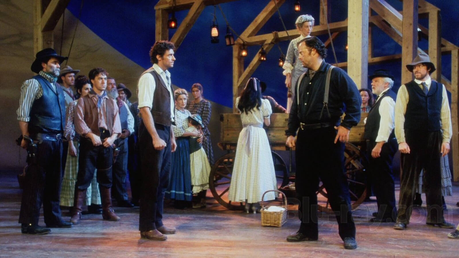 Curly (Hugh Jackman) and Jud Fry (Shuler Hensley) face-off. Both look agitated as people anticipate what's to come in the background.