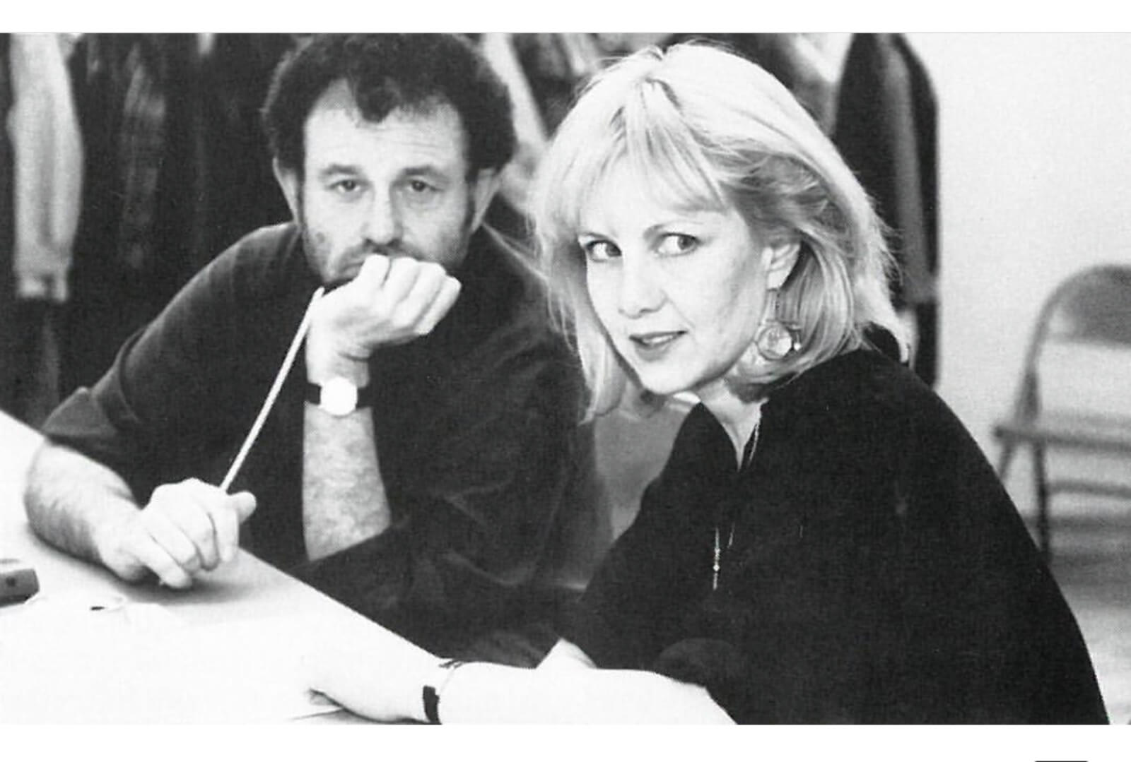 Mike Ockrent and Susan Stroman in rehearsal. Mike is holding a baton and looking at the camera while Stro is looking to the left at something happening in the room.