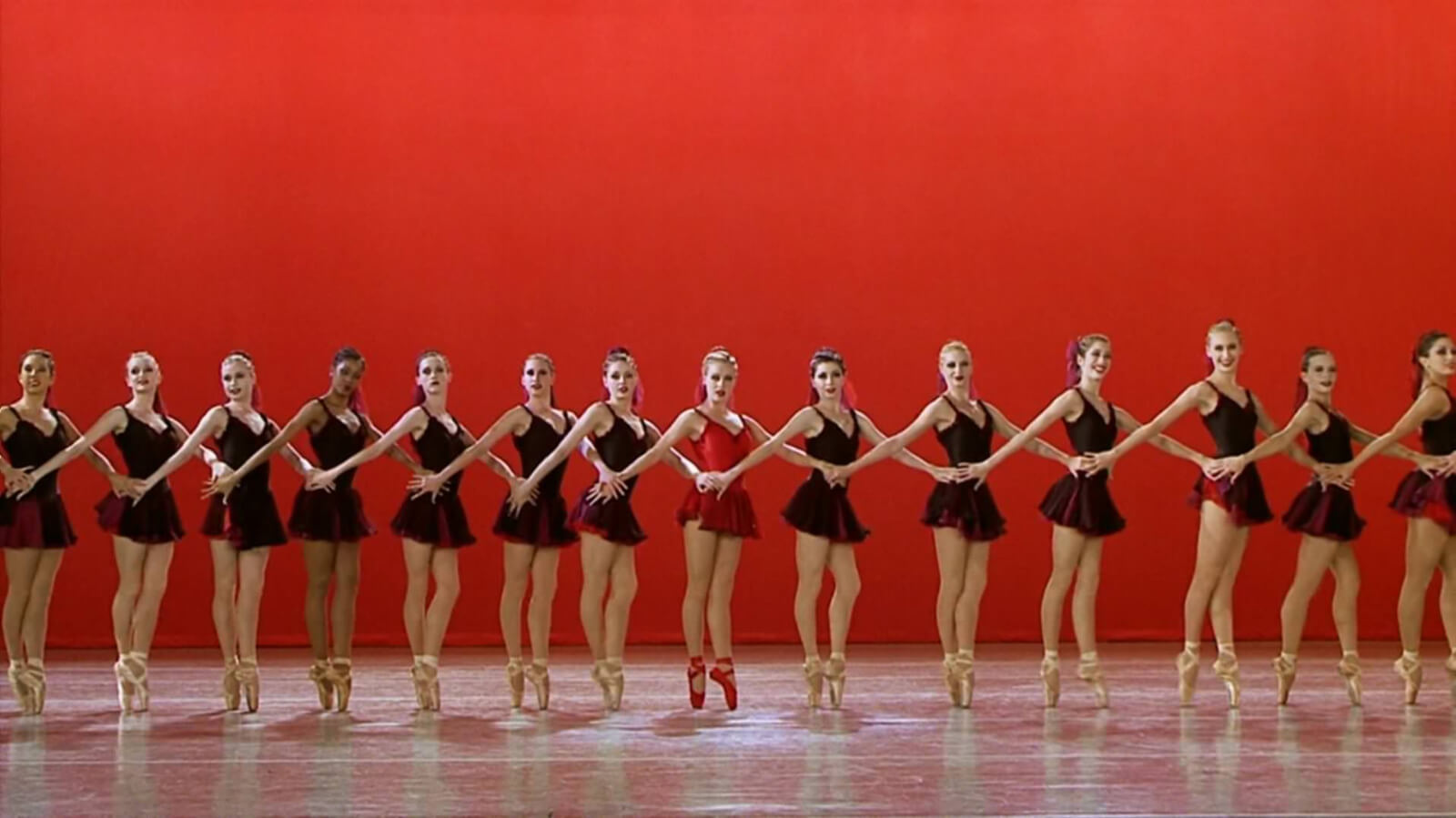 Amanda Schull with dancers in the finale "Canned Heat" from Center Stage. They are in a line across the stage with Amanda Schull center stage in a bright red costume. 