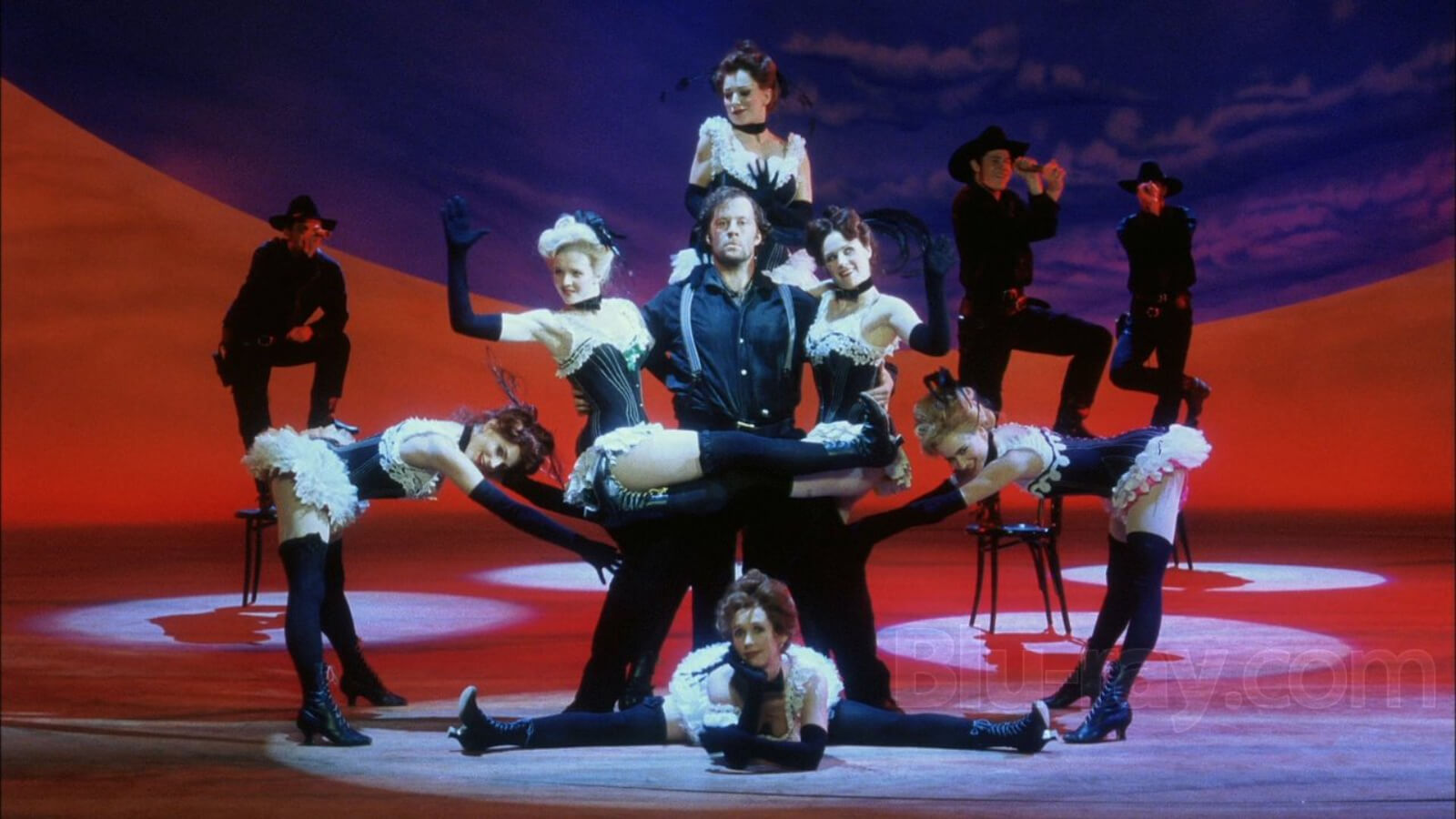 The Dream Ballet Postcard Girls in sexy outfits surround Jud Fry (Shuler Hensley) wearing a black ensemble with suspenders.