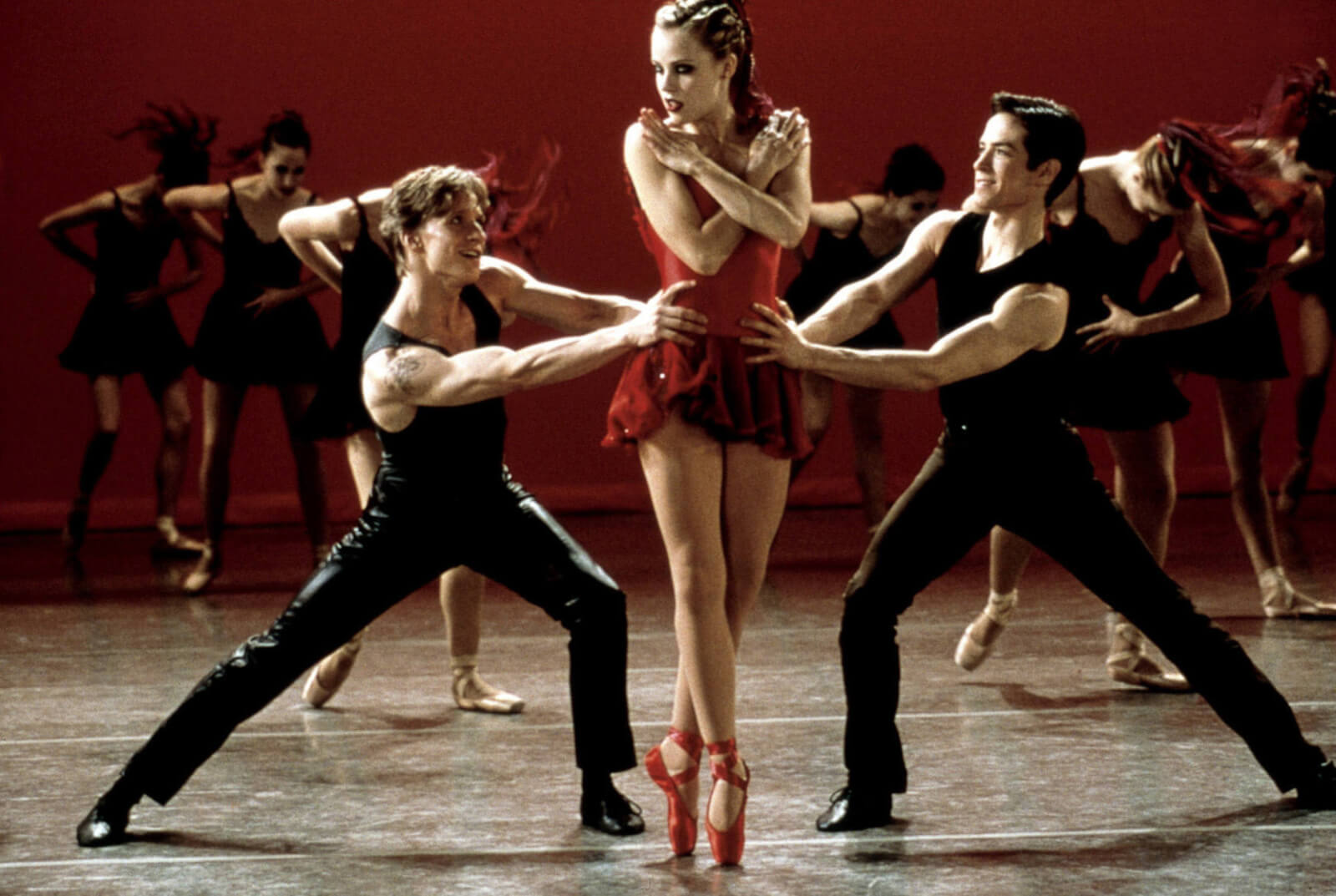 Ethan Stiefel, Amanda Schull and Sascha Radetsky performing the finale in "Canned Heat" from Center Stage. She is in a red costume with red pointe shoes. The men have their hands on her waist vying for her attention. 