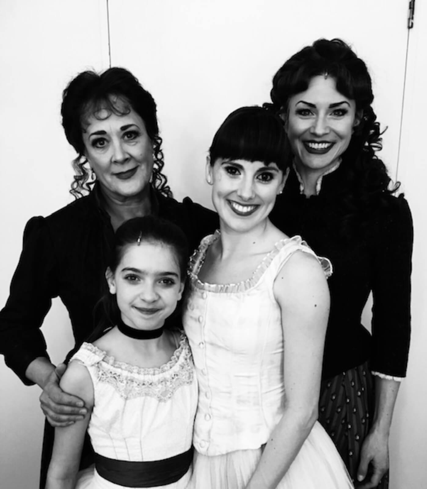 A black and white photo of Marie (in her character's costume) and her family, in formal wear.